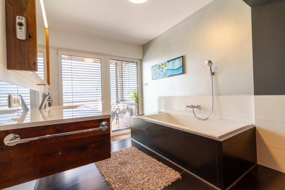 Modernes Badezimmer mit Badewanne, Holzwaschtisch und Zugang zur Terrasse.
