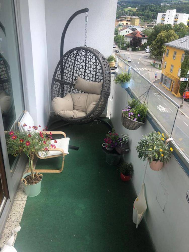 Möblierter Balkon mit Hängesessel, Pflanzen und Stadtblick.