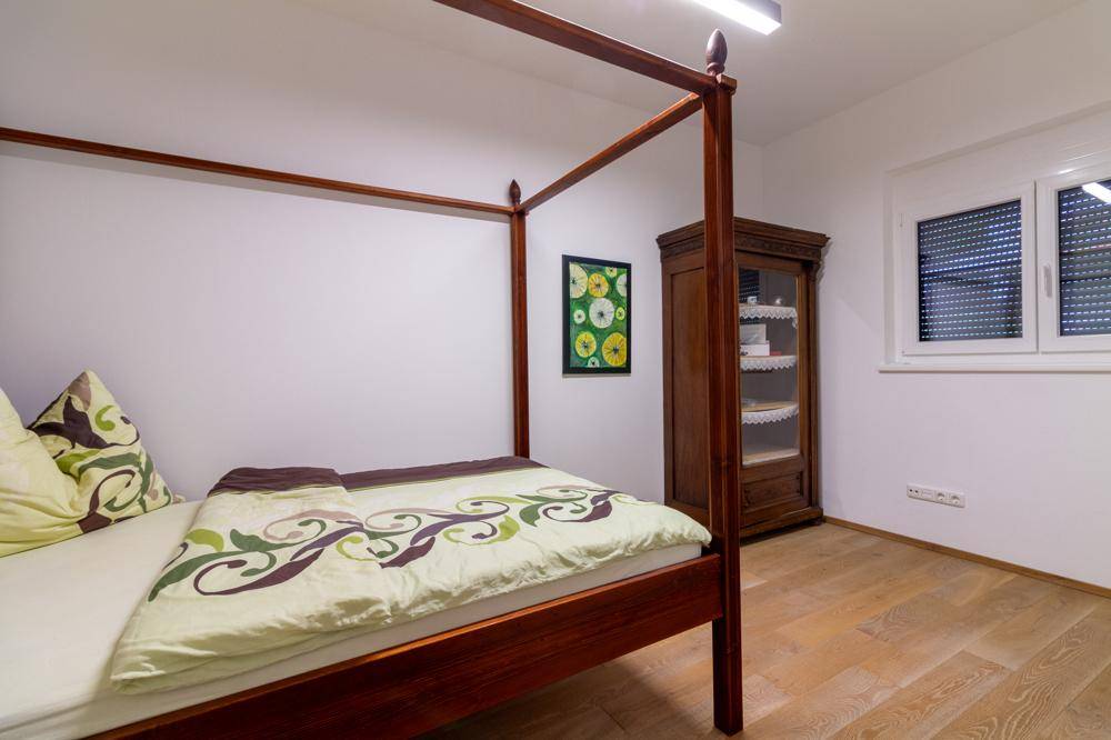 Schlafzimmer mit Himmelbett, Holzboden und antikem Schrank.