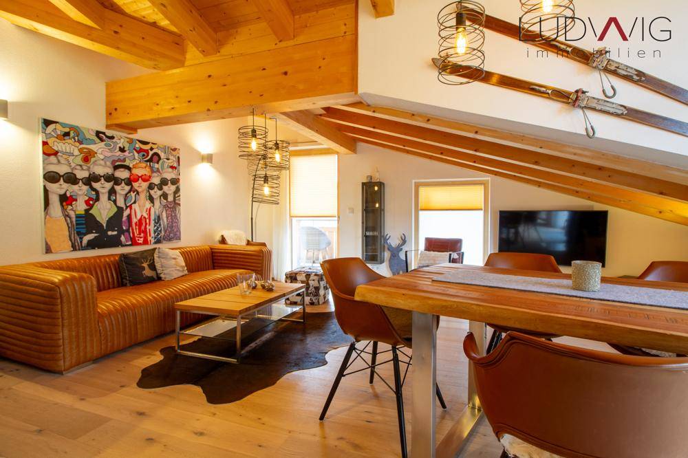 Geräumiger Wohn-Essbereich mit Holzbalkendecke, bequemer Couch und modernem Esstisch.