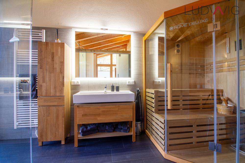 Luxuriöses Badezimmer mit integrierter Sauna, modernem Waschtisch und beheiztem Handtuchhalter.