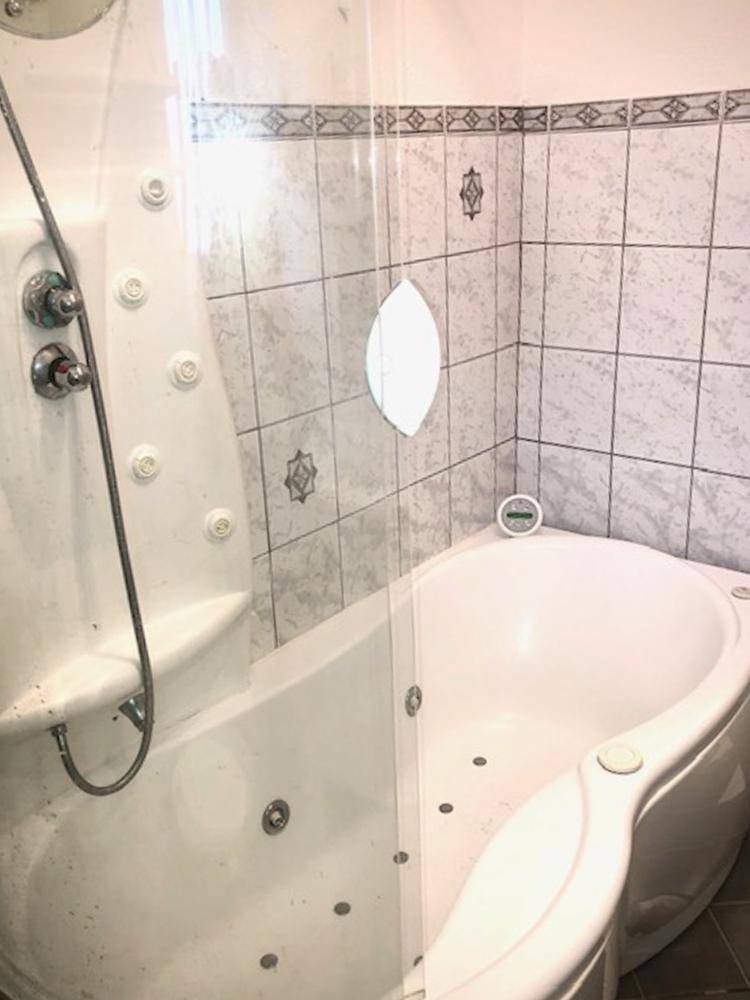 Badezimmer mit Eckbadewanne, integrierter Dusche und Fliesen.