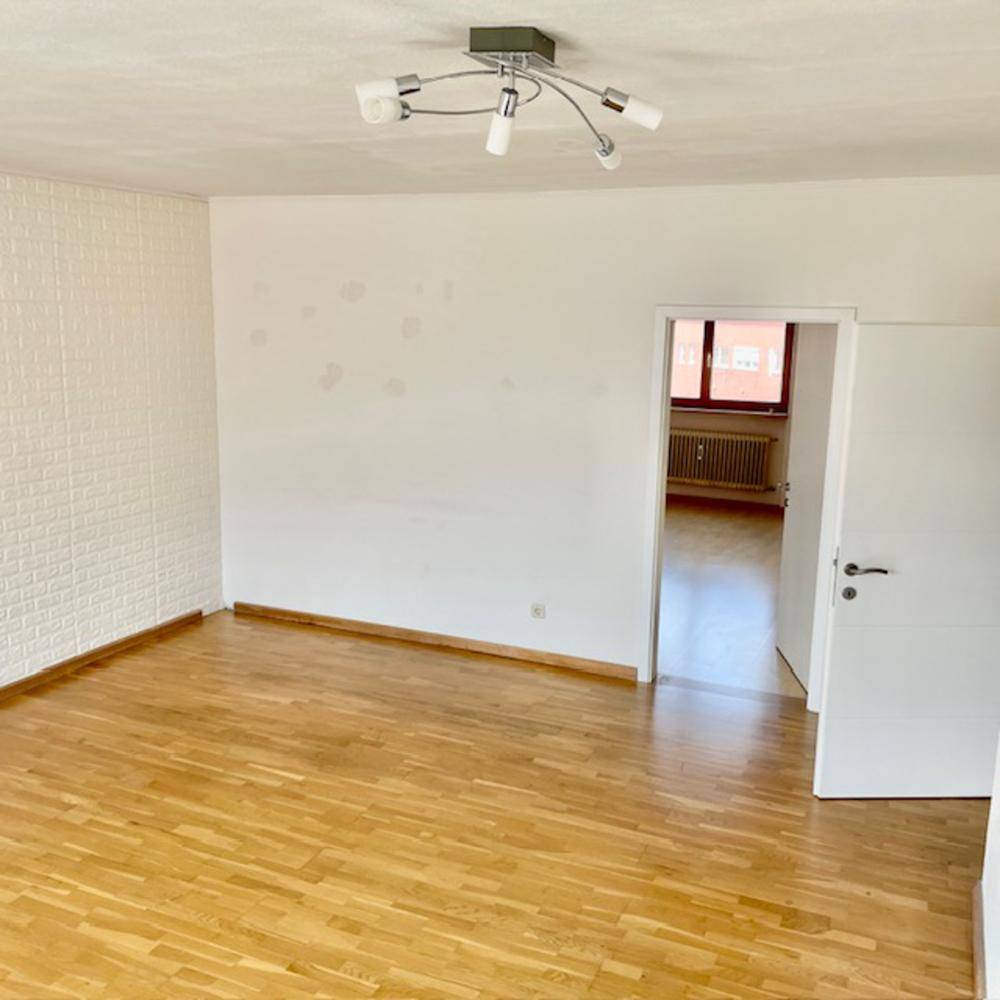Leerer Raum mit Holzboden und weißer Ziegelwand.