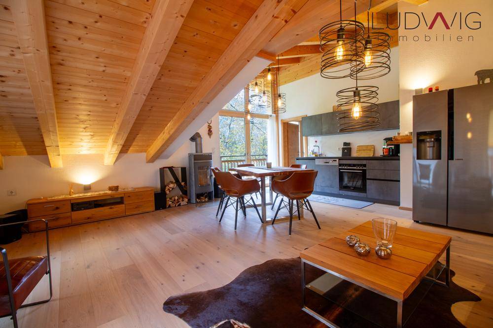 Offener Wohn-Essbereich mit Holzbalkendecke, Kaminofen und moderner Küche.