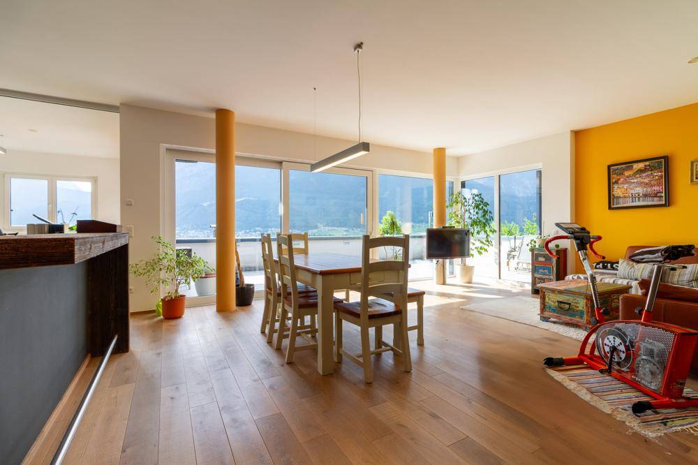 Heller Wohn- und Essbereich mit Holzboden, Bergblick und Zugang zur Terrasse.