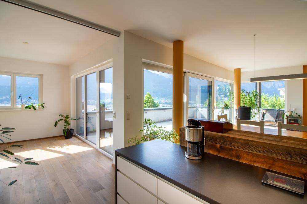 Offener Wohnbereich mit Küche, Essbereich und weitem Bergblick durch große Fenster.