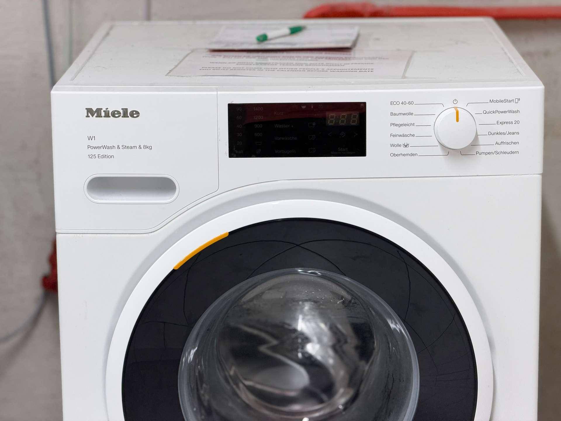 Nahaufnahme einer modernen Miele Waschmaschine, bereit für den Gebrauch im Waschraum.