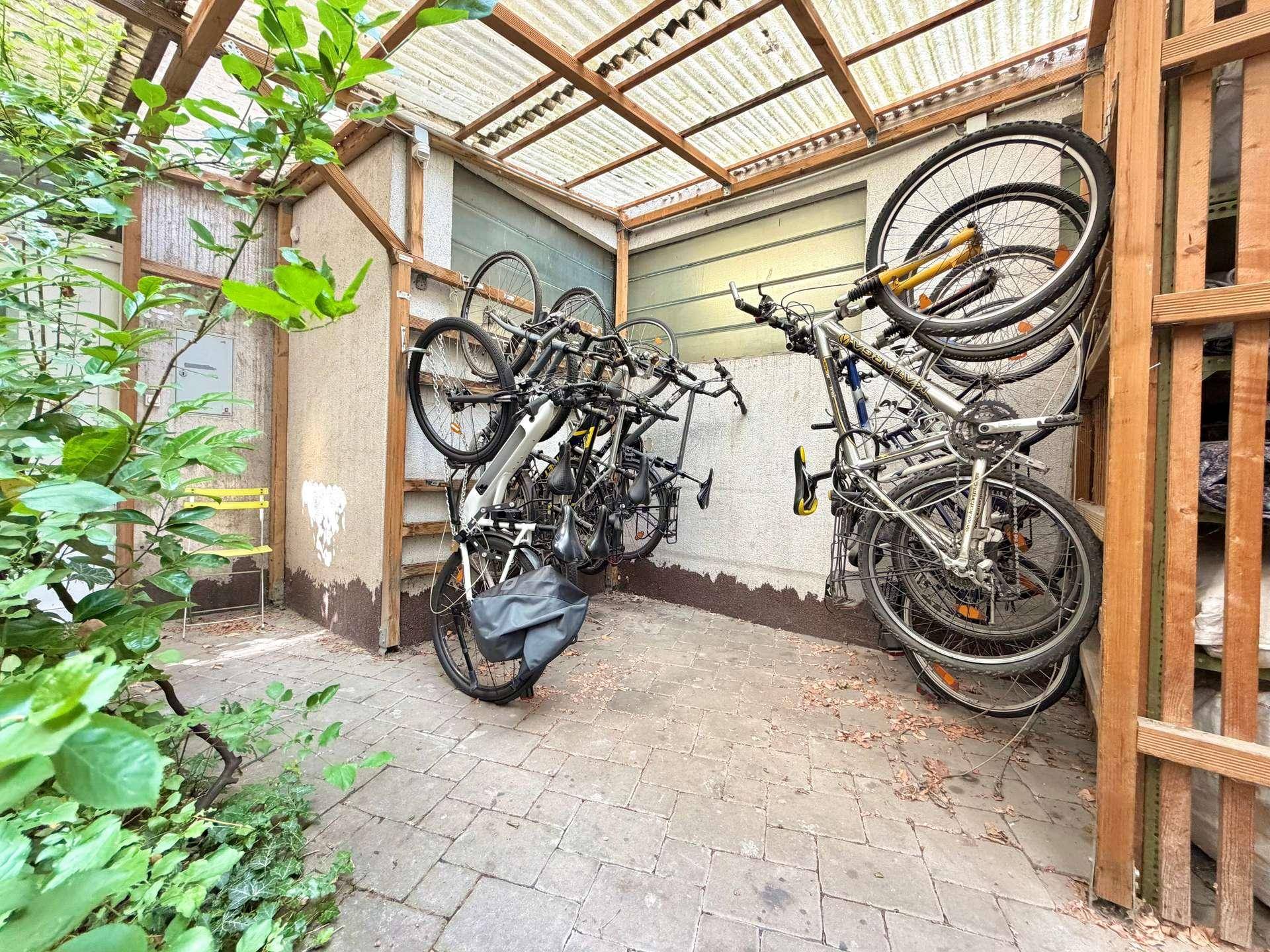 Überdachter Fahrradabstellbereich mit mehreren Fahrrädern, effizient vertikal gelagert.