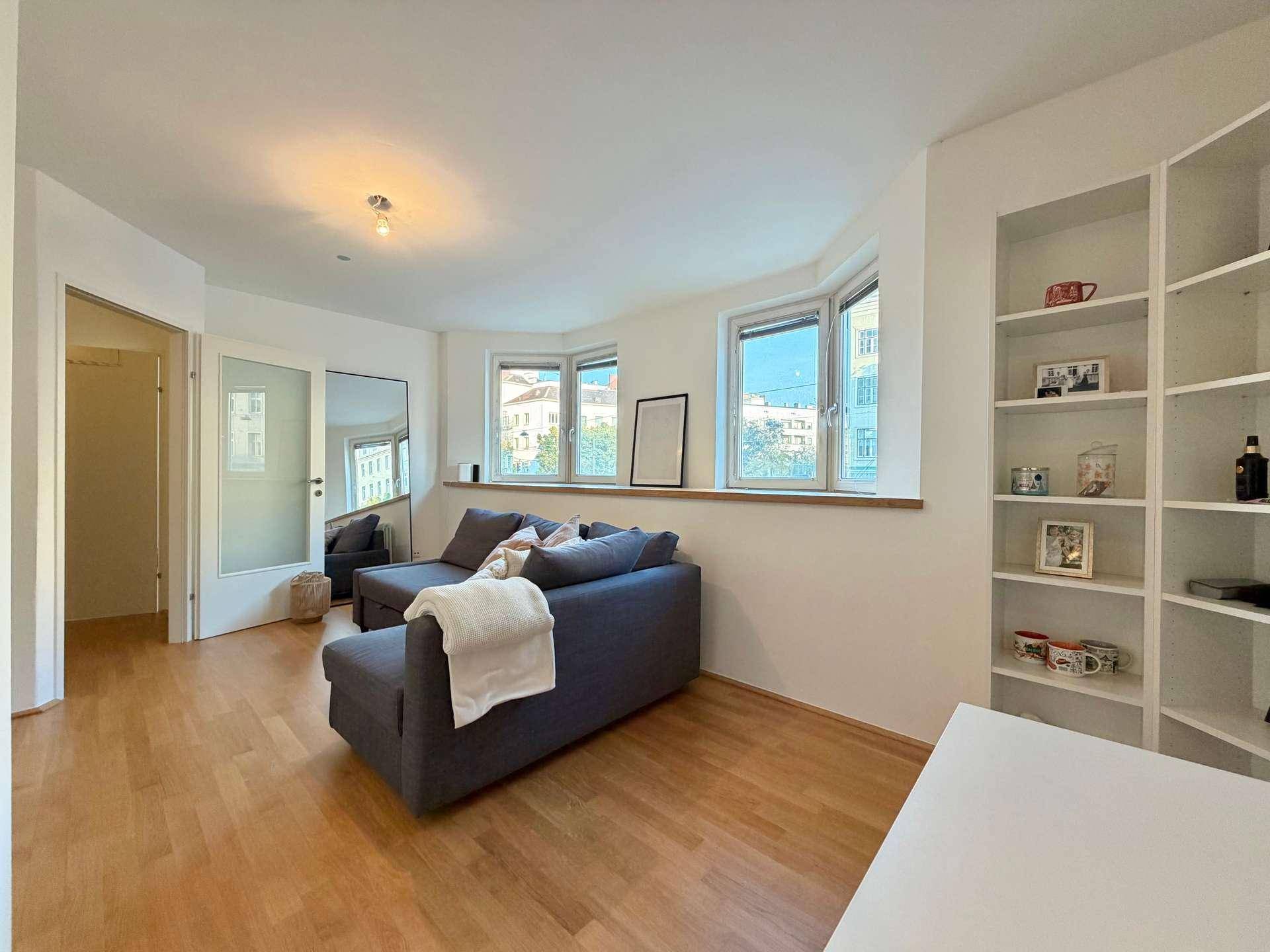 Geräumiges Wohnzimmer mit Sofa, Holzfußboden und großem Wandspiegel.