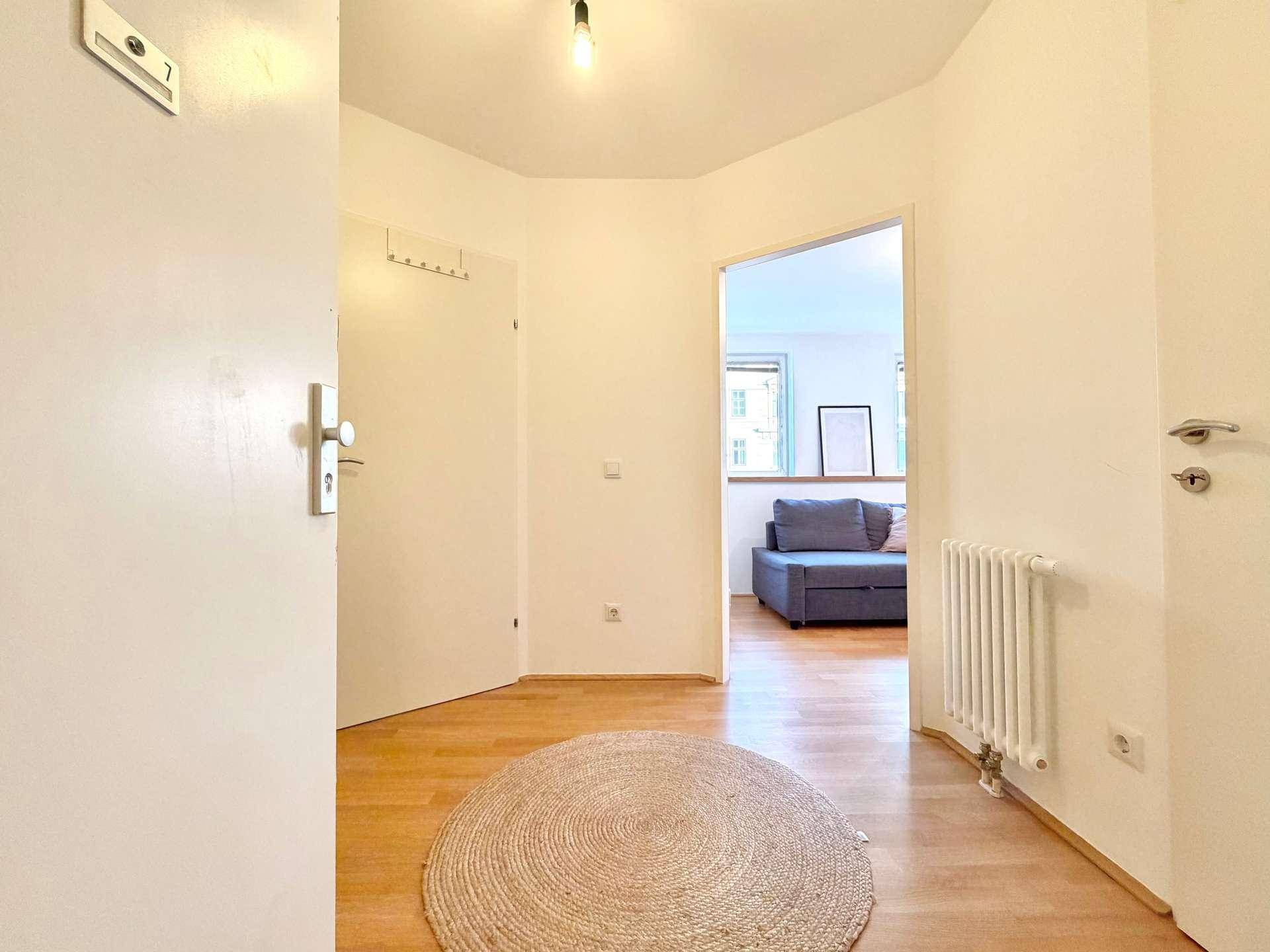 Heller Eingangsbereich mit Holzfußboden und Blick in den Wohnbereich.
