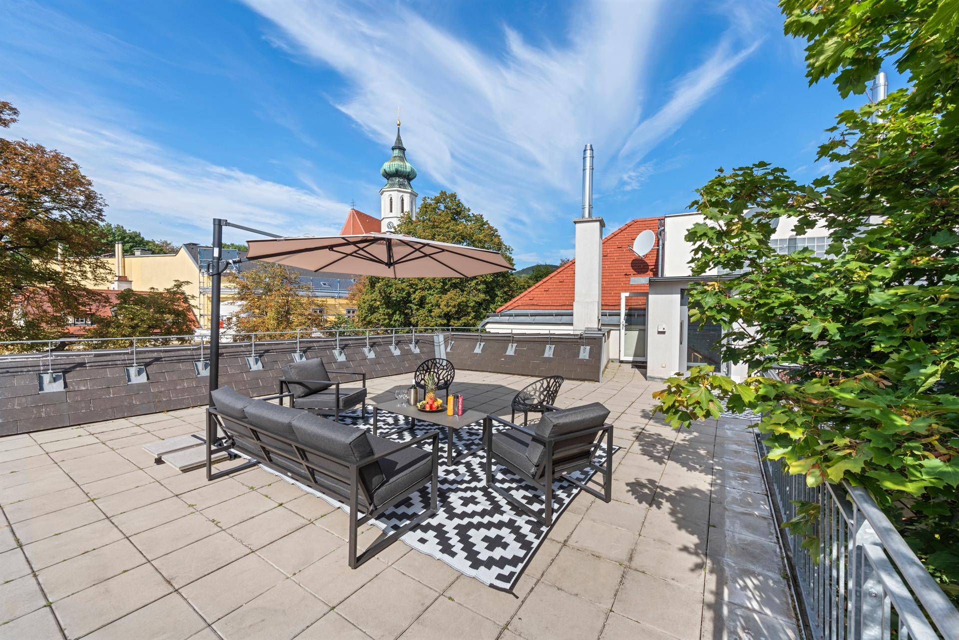Großzügige Dachterrasse mit moderner Lounge-Möblierung und weitem Blick über die Stadt.