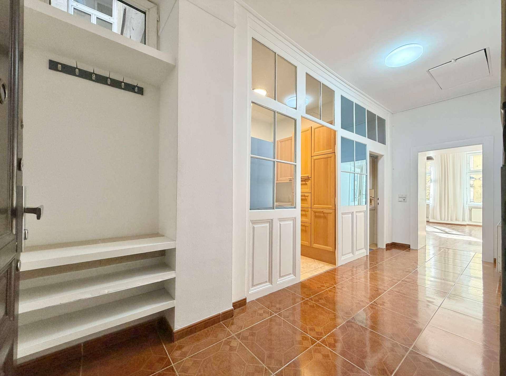 Heller Flur mit Terrakotta-Fliesenboden und integrierter Garderobe, der zur Küche führt.