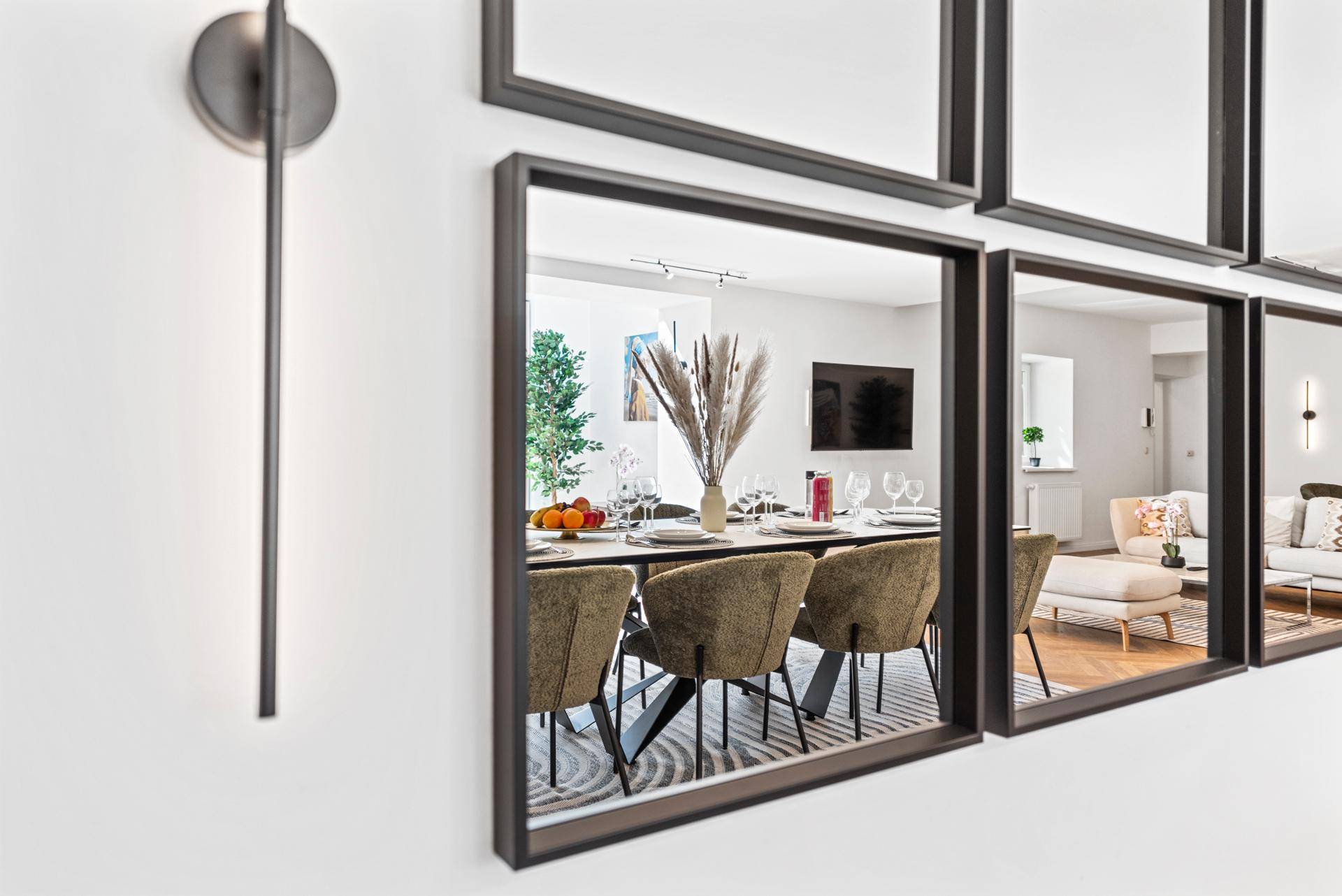 Detailansicht des Esstisches mit moderner Dekoration und reflektierenden Wandspiegeln.
