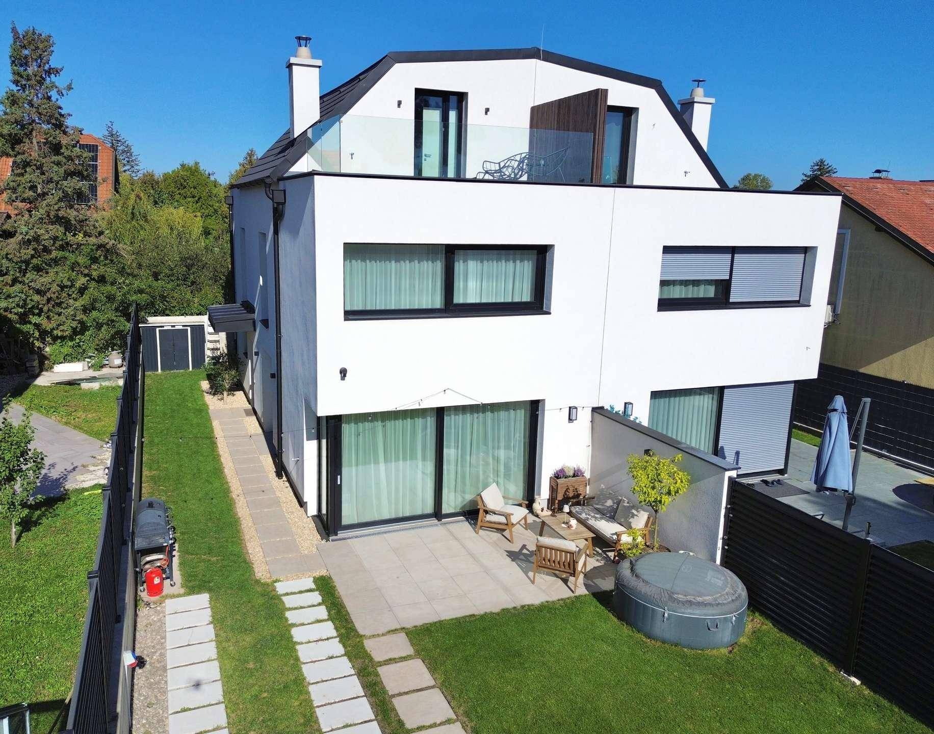 Luftaufnahme eines modernen Hauses mit Garten, Terrasse, Whirlpool und Dachterrasse.