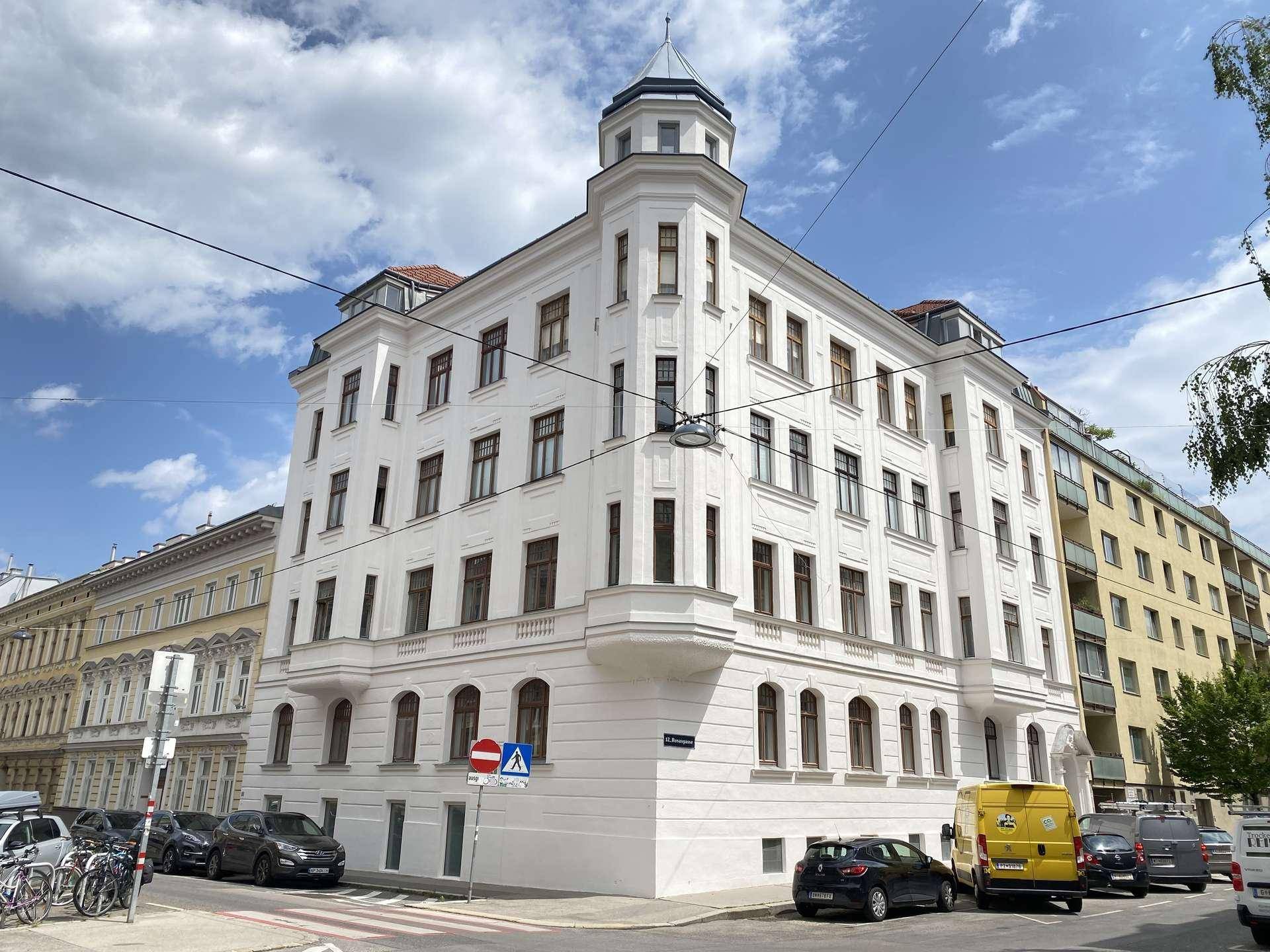 Historisches Eckgebäude mit klassischer Architektur, vielen Fenstern und einem Turmerker.