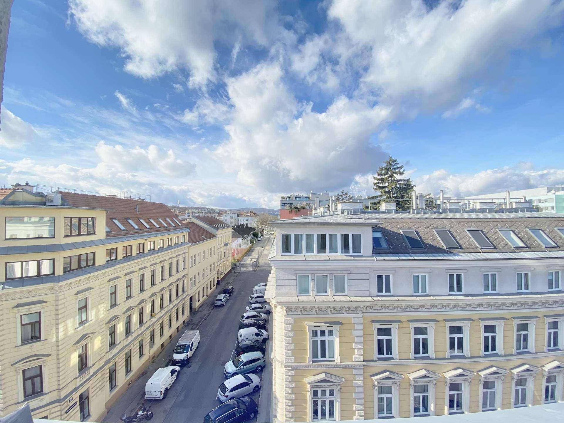 Panoramablick über eine städtische Straße mit historischen Gebäuden und geparkten Autos.