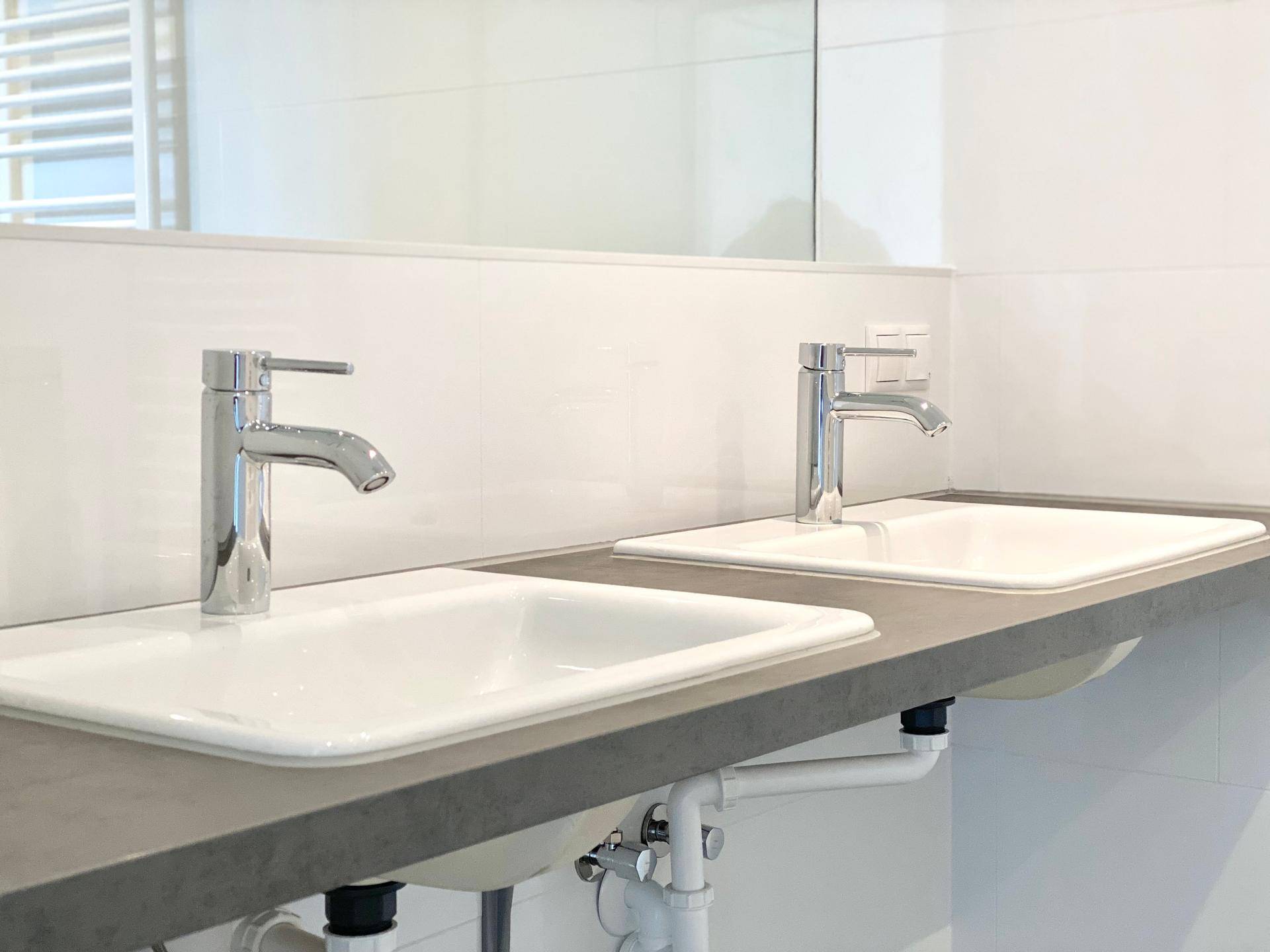 Nahaufnahme der modernen Doppelwaschbecken mit Armaturen im Badezimmer.