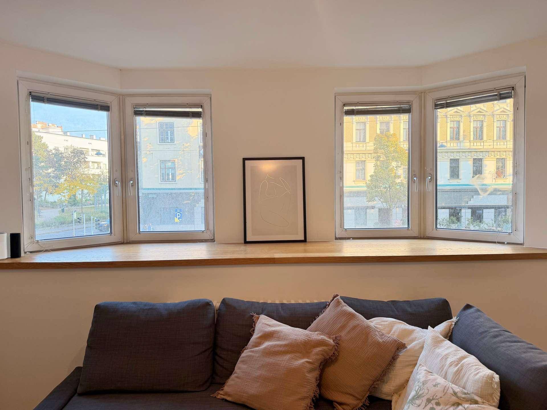 Helle Fensterfront im Wohnzimmer mit Blick auf die umliegenden Gebäude.