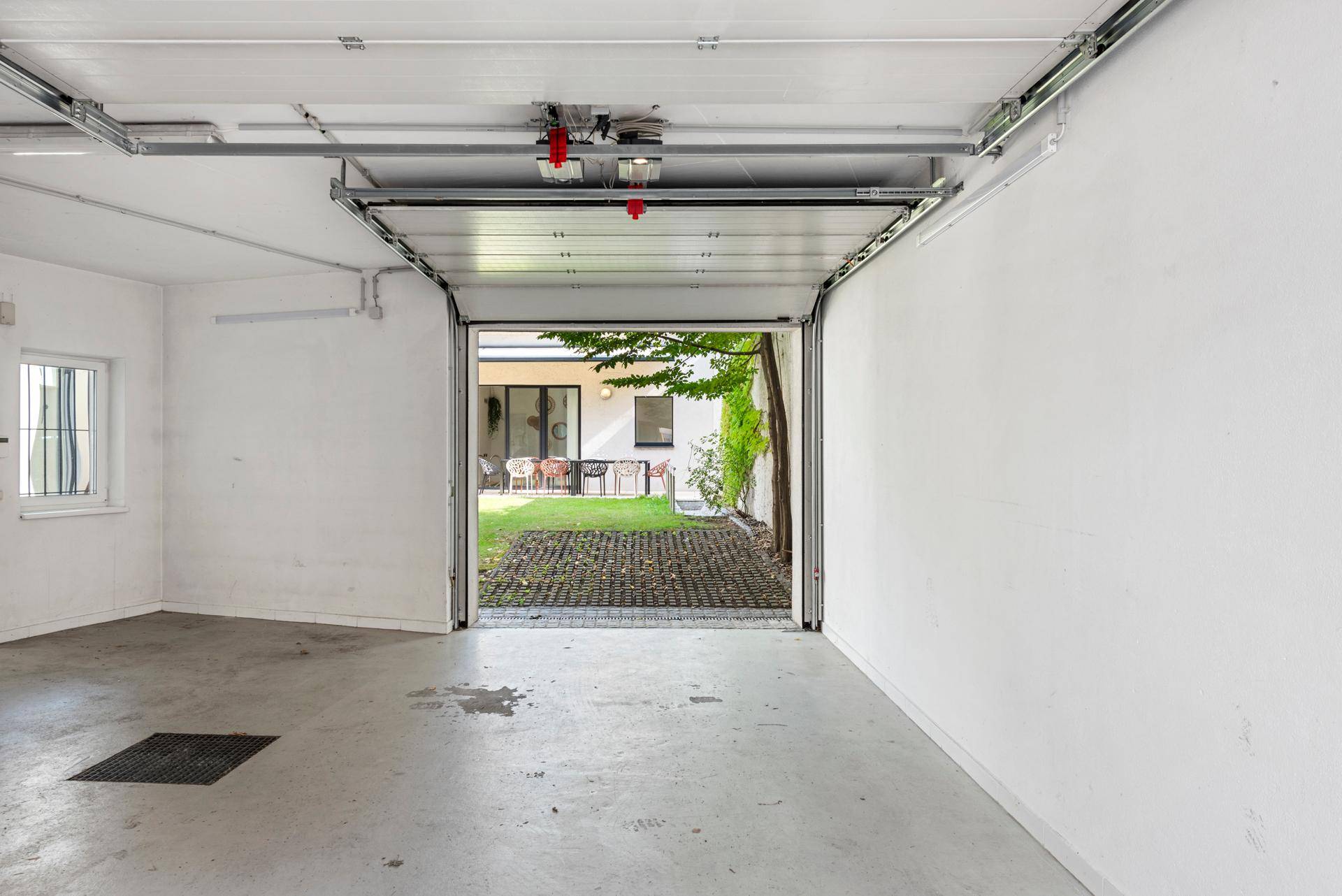 Geräumige Garage mit offenem Tor und Blick auf den hinteren Gartenbereich.