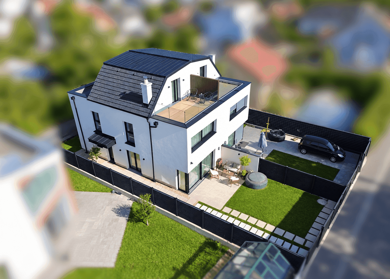 Luftaufnahme eines modernen Einfamilienhauses mit Garten, Dachterrasse und Parkplatz.