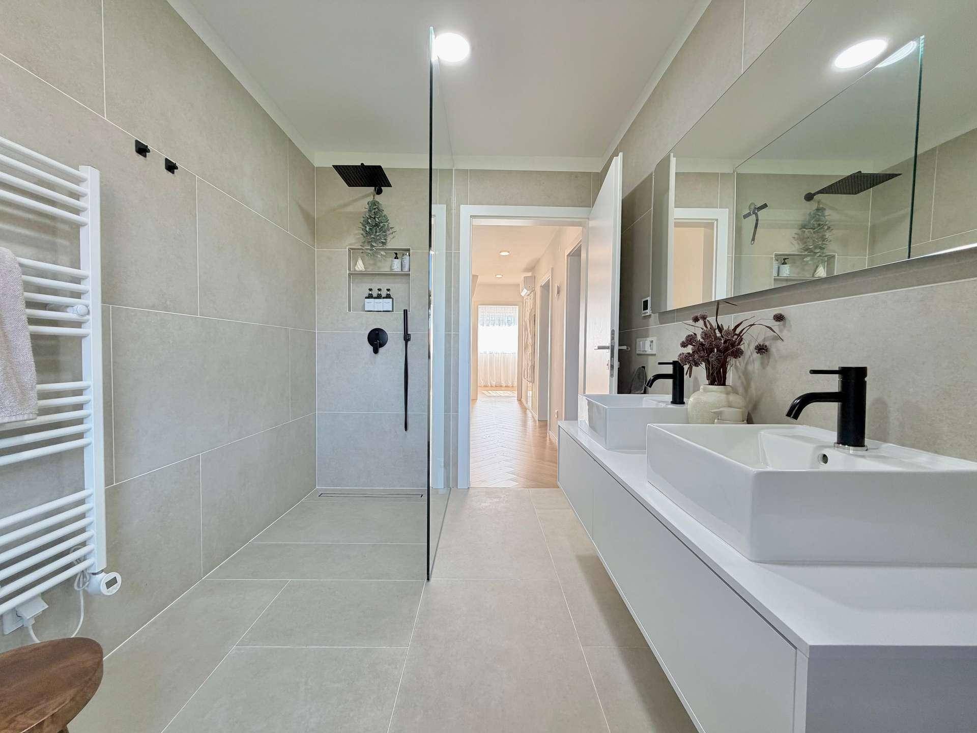 Blick auf die geräumige begehbare Dusche und den Doppelwaschtisch im modernen Bad.