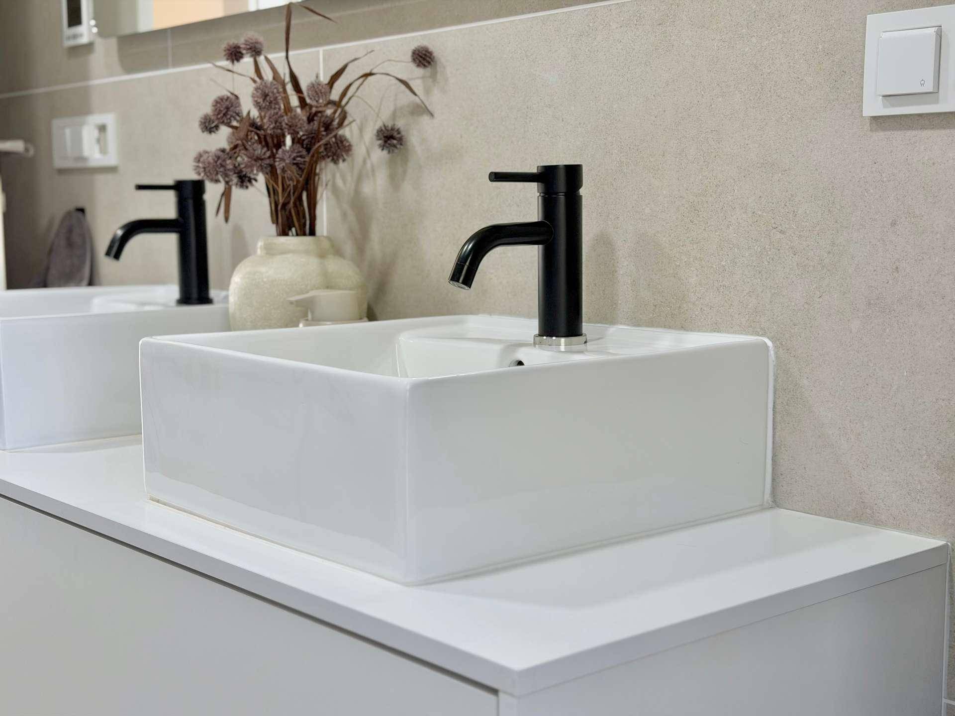 Nahaufnahme eines modernen Waschbeckens mit schwarzem Wasserhahn im Badezimmer.