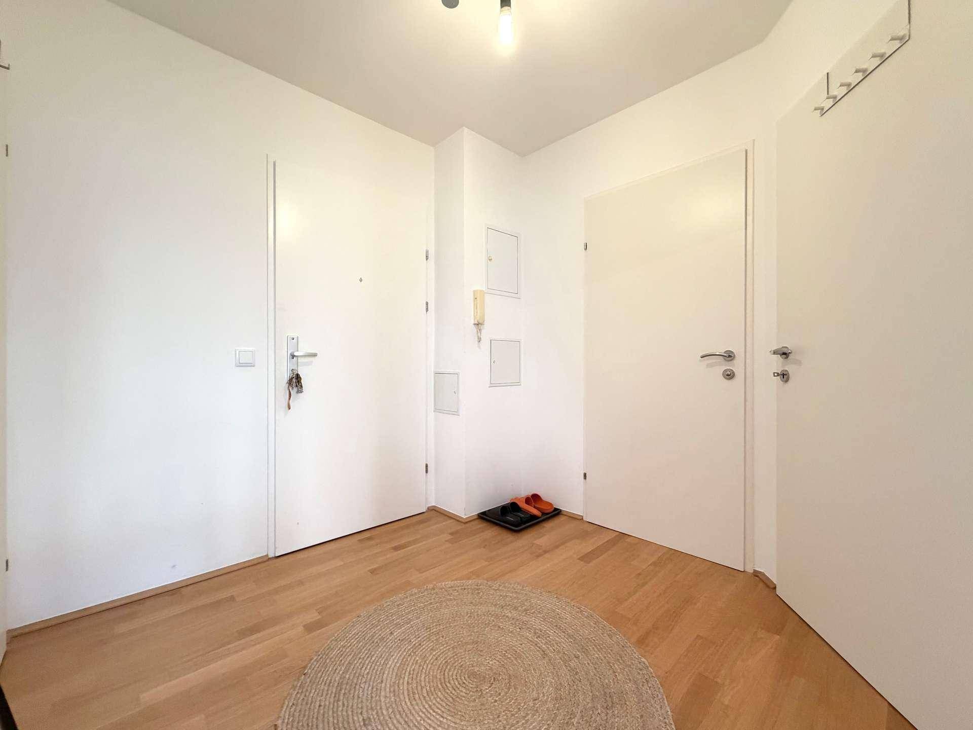 Heller Eingangsbereich mit mehreren Türen und Holzfußboden.