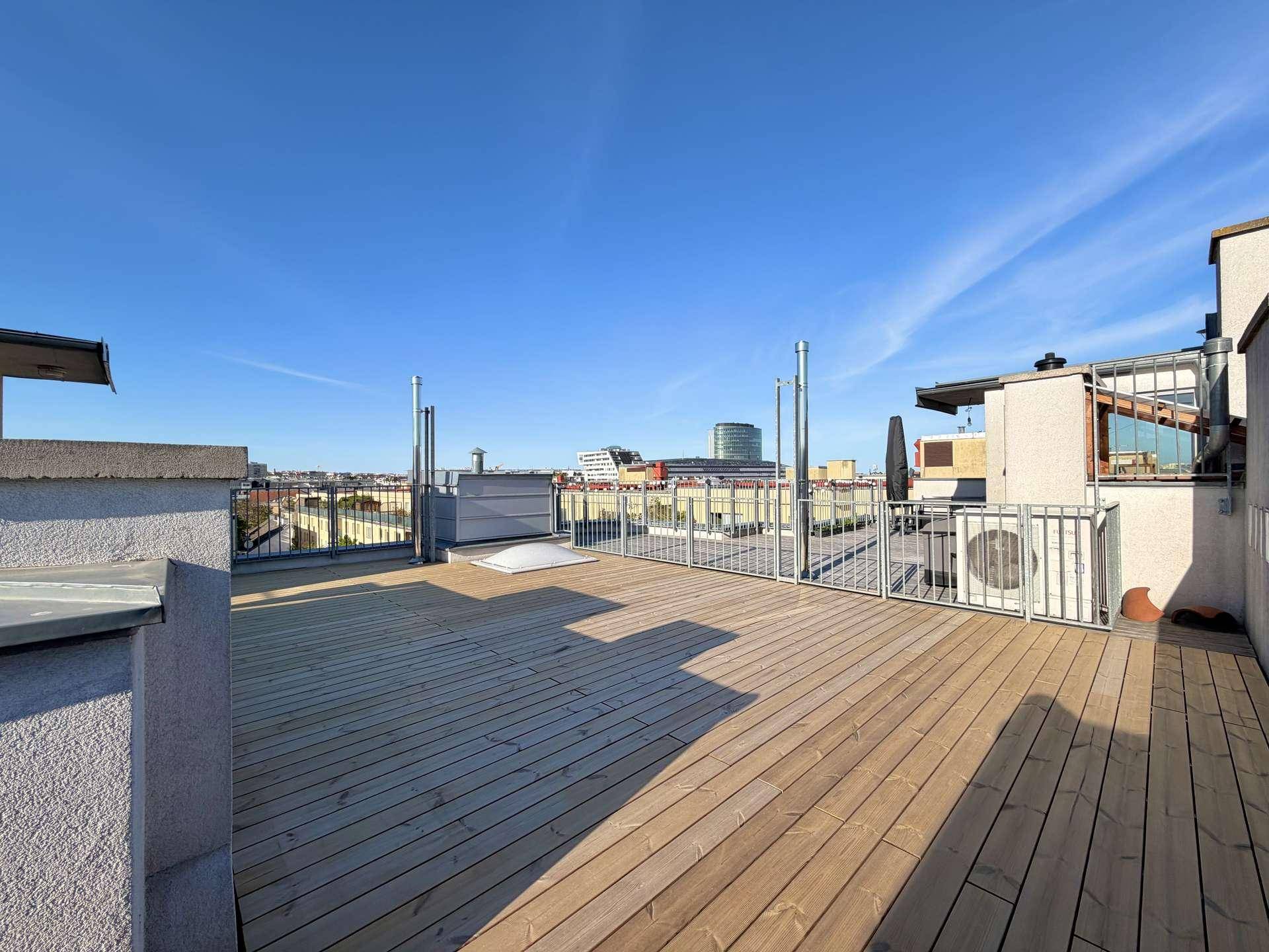 Große Dachterrasse mit Holzboden, Metallgeländer und Klimaanlage, ideal zum Entspannen.