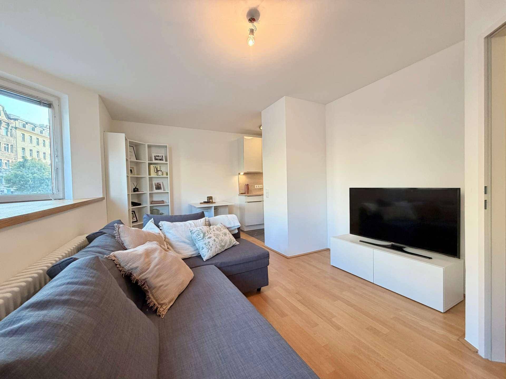 Geräumiges Wohnzimmer mit großem Ecksofa, Fernseher und Blick auf die Stadt.