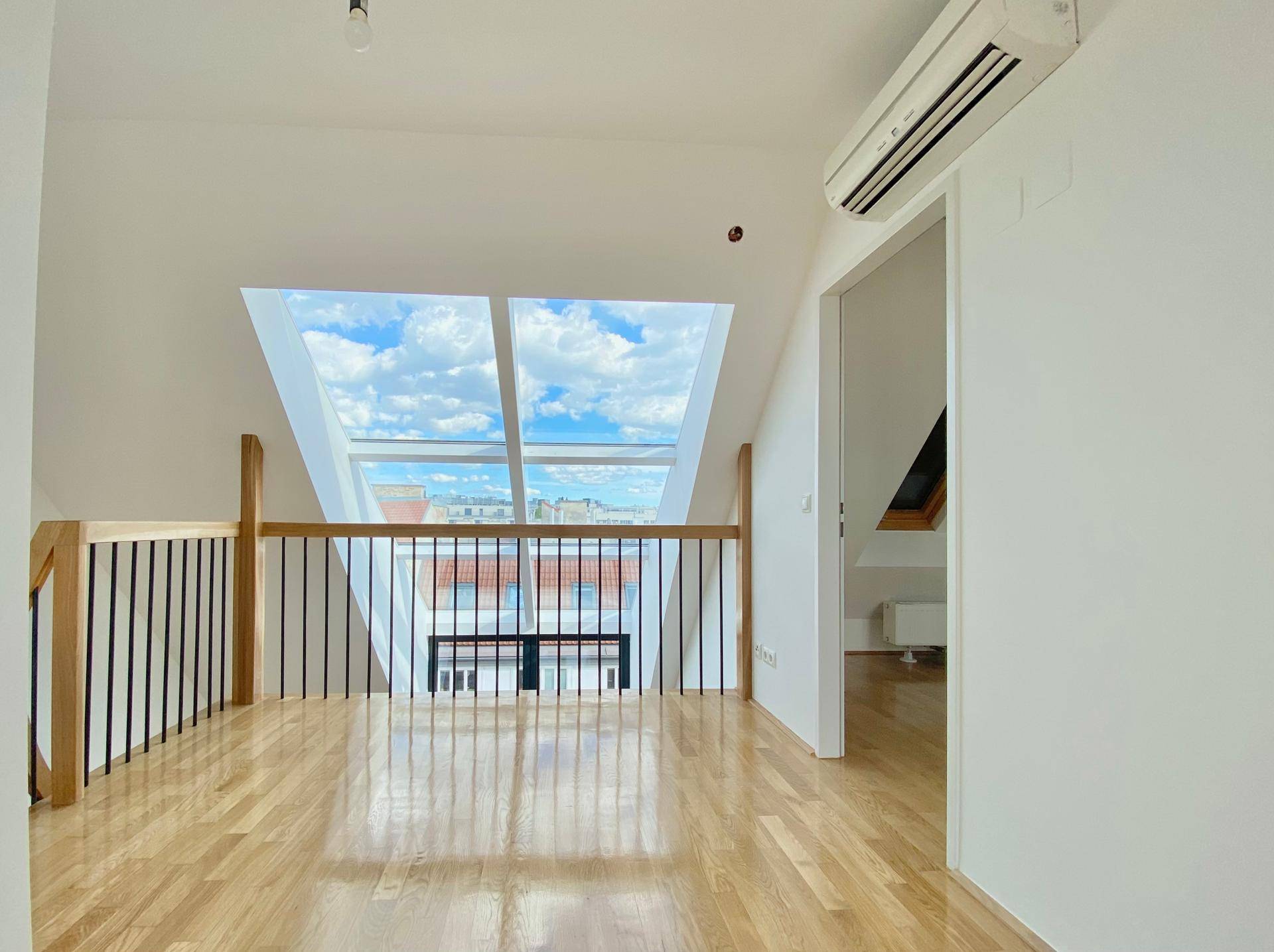 Heller Galeriebereich mit Blick auf die Stadt durch große Dachfenster und Klimaanlage.