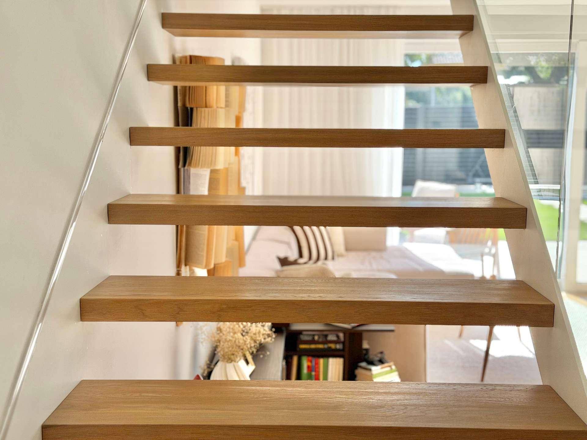 Blick auf die eleganten Holzstufen der Treppe mit transparentem Glasgeländer.