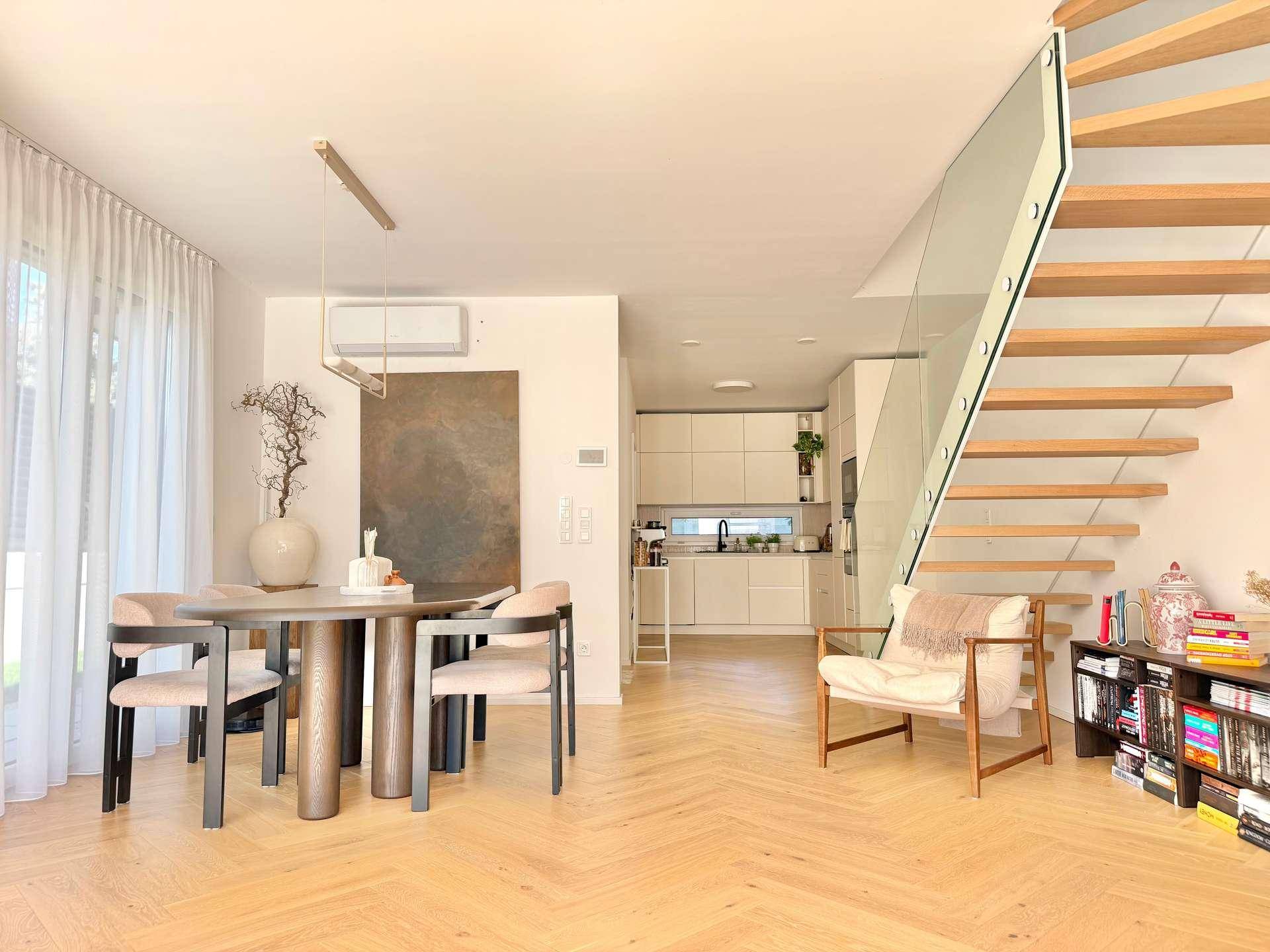 Eleganter Essbereich mit modernem Tisch und Stühlen, offen zur Küche und Treppe.