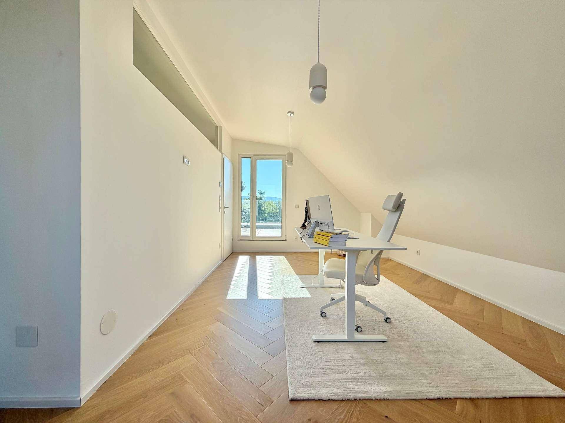 Weitläufiges Büro im Dachgeschoss mit schrägen Wänden und sonnigem Ausblick.