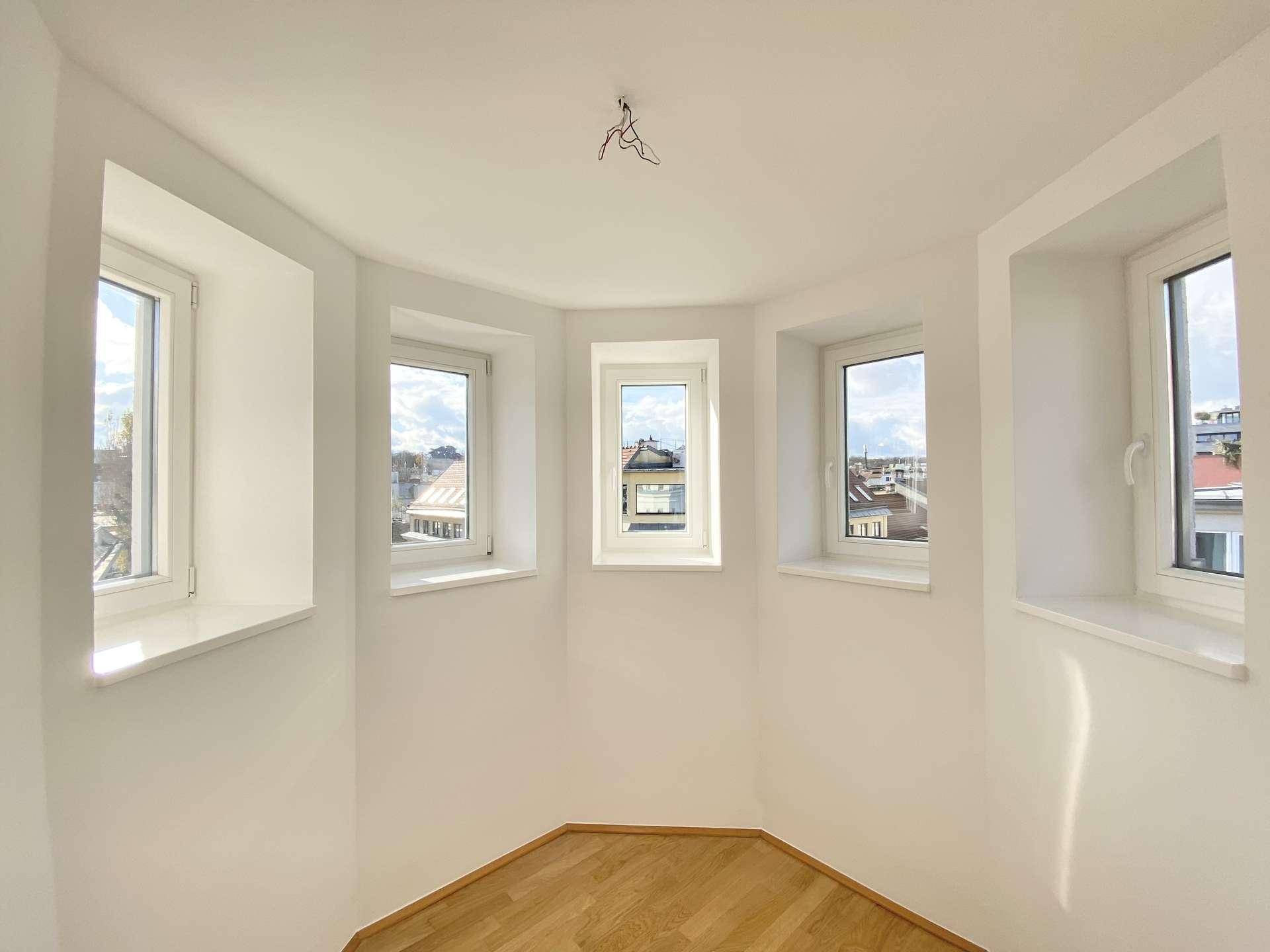 Heller Erkerbereich mit mehreren Fenstern, die einen Panoramablick auf die Umgebung bieten.