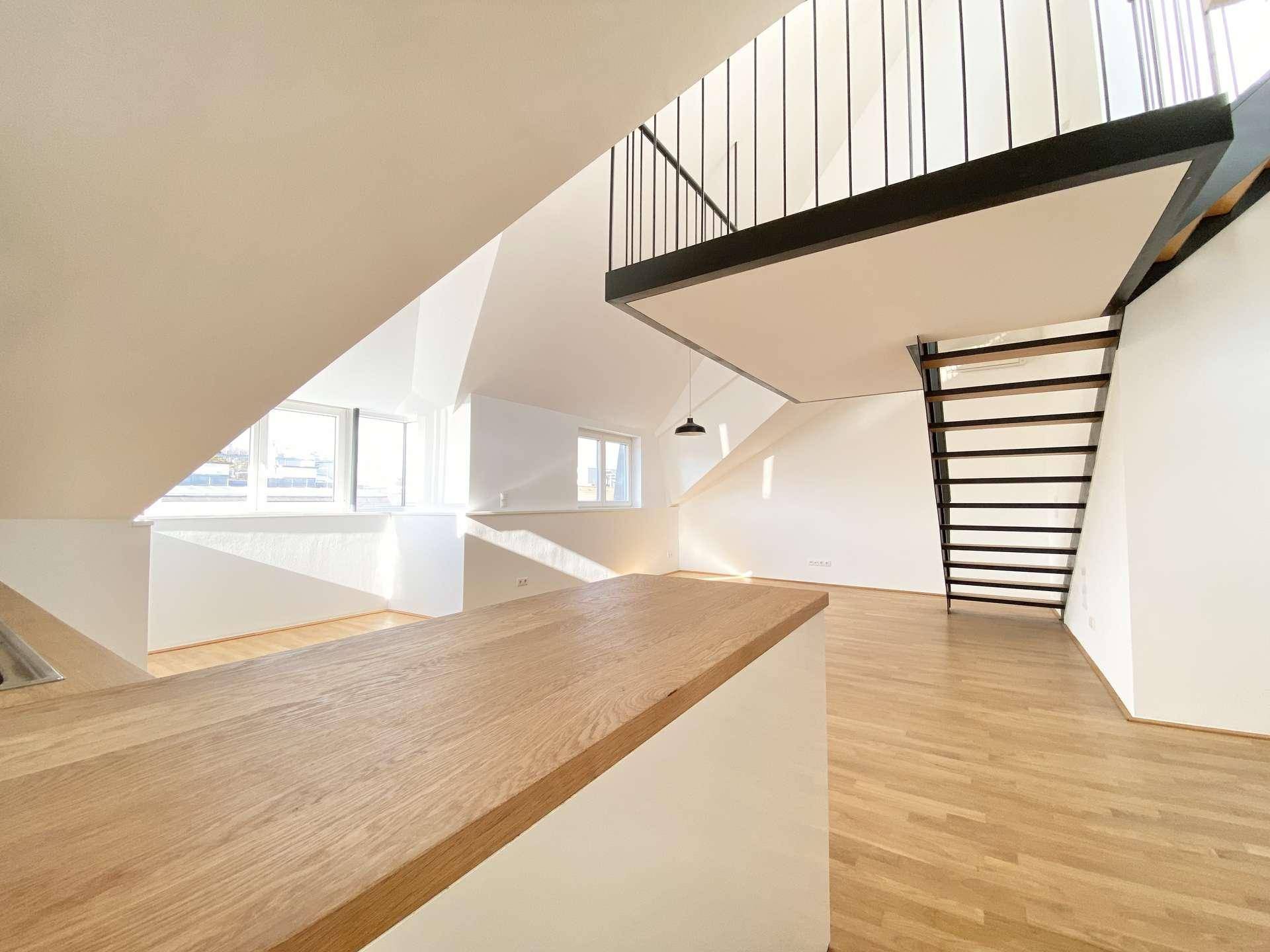 Heller Wohnbereich mit Holzboden, offener Treppe und Holztheke, ideal für offenes Wohnen.
