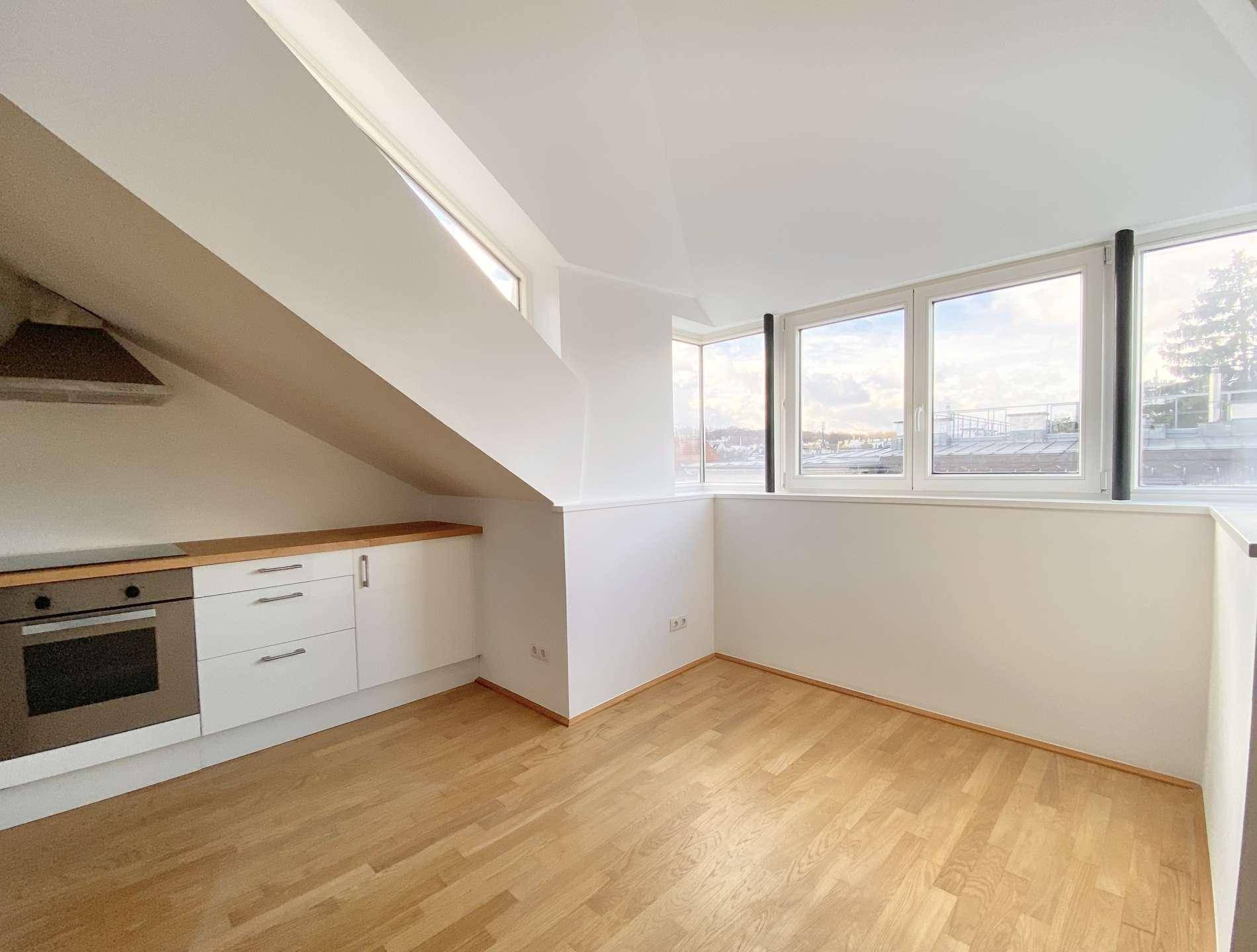 Heller Küchenbereich mit Holzfußboden, weißen Schränken und großen Fenstern mit Stadtblick.
