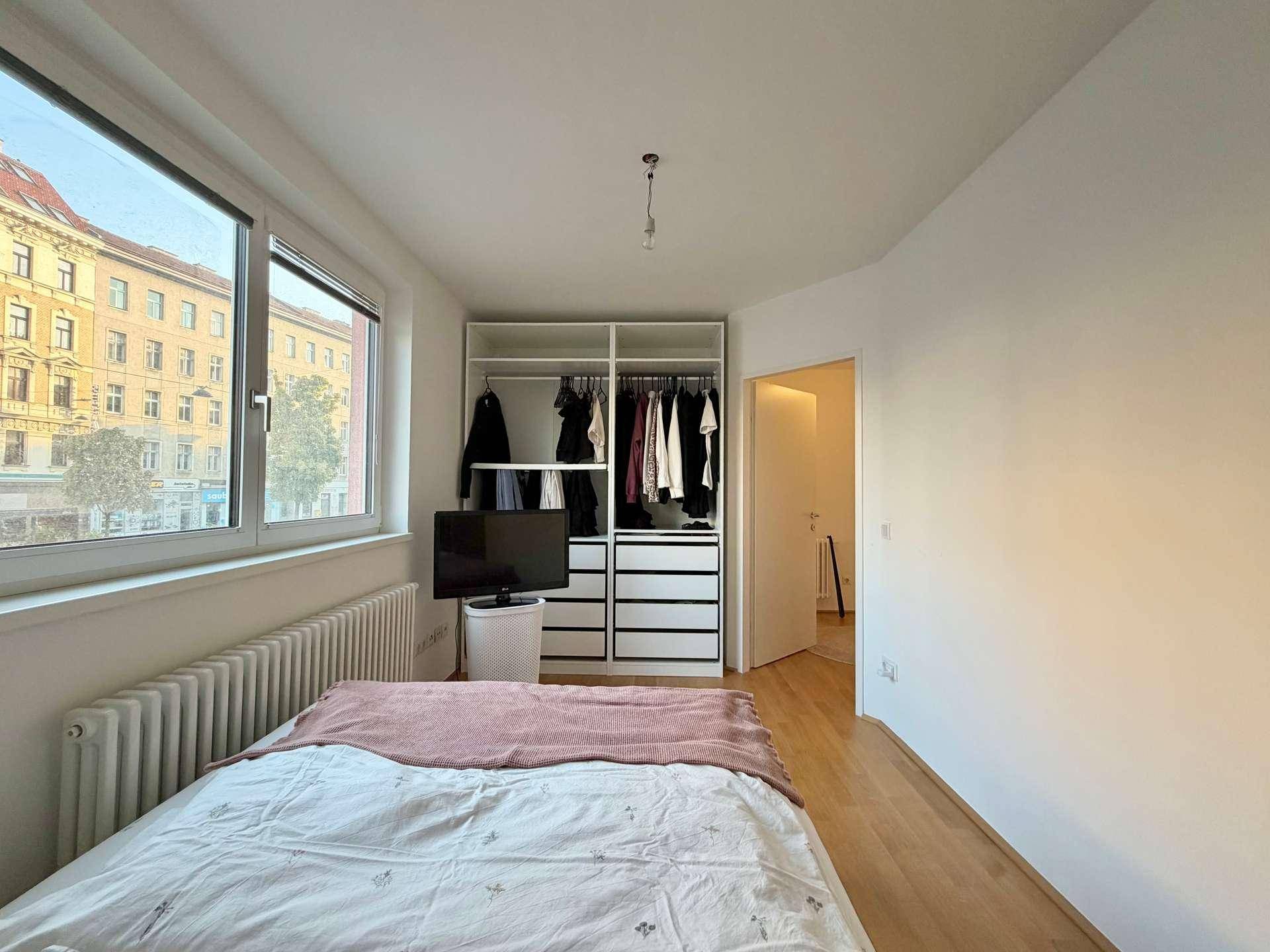 Schlafzimmer mit Doppelbett, offenem Kleiderschrank und Blick auf die Stadt.