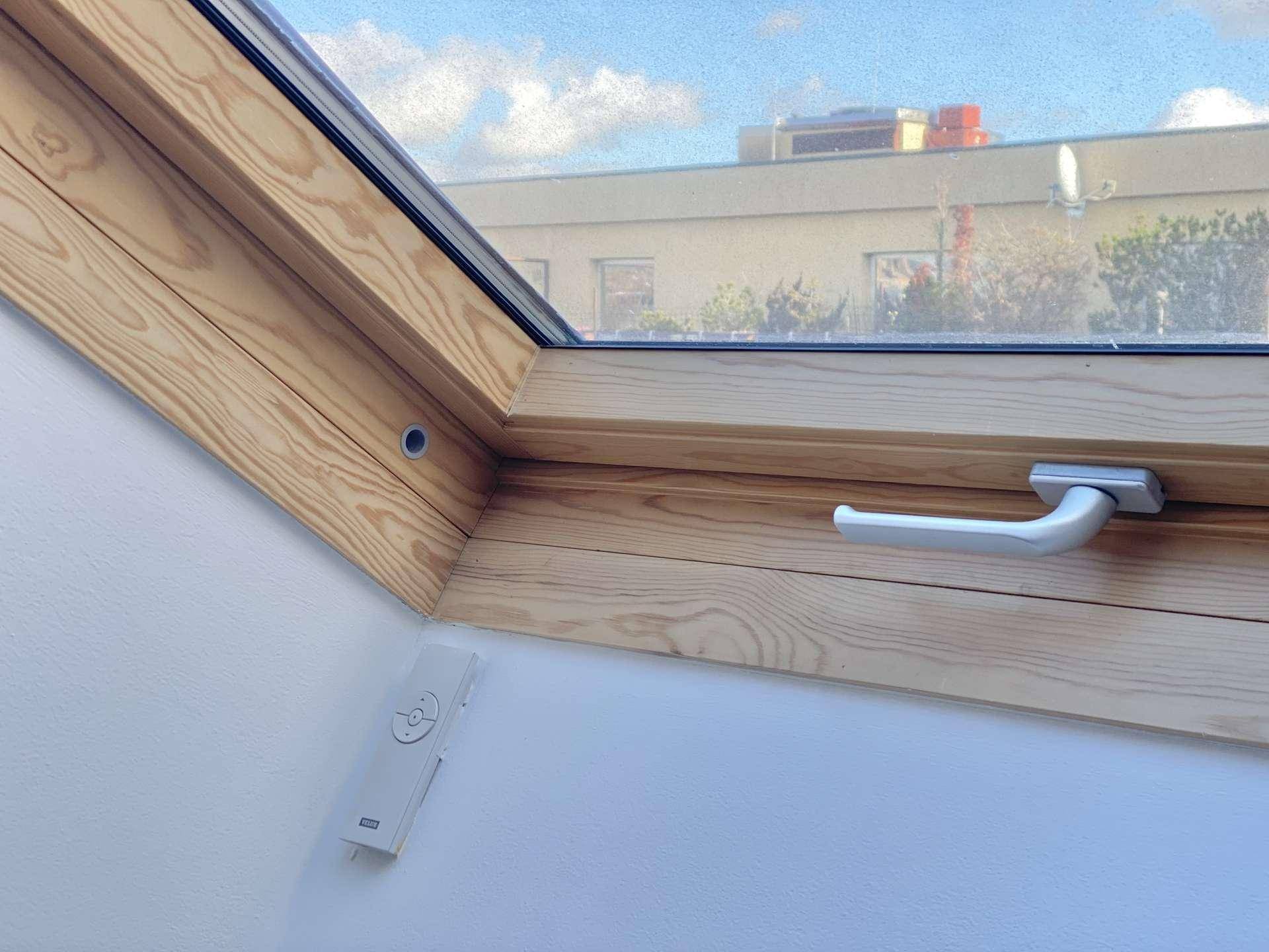 Detailansicht eines Holz-Dachfensters mit integrierter Fernbedienung für Komfort.