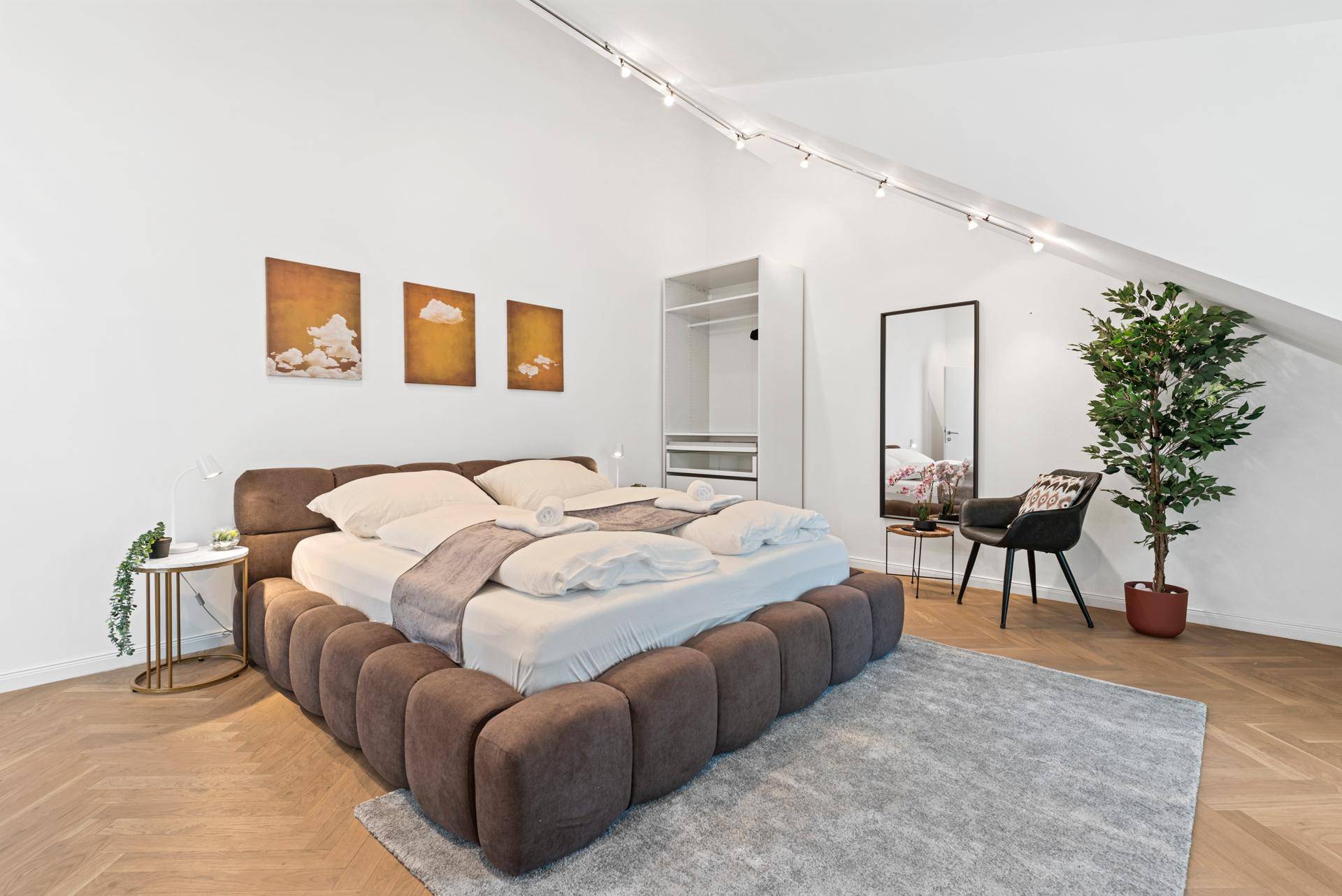 Schlafzimmer im Dachgeschoss mit gemütlichem Bett, offenem Kleiderschrank und schrägen Wänden.
