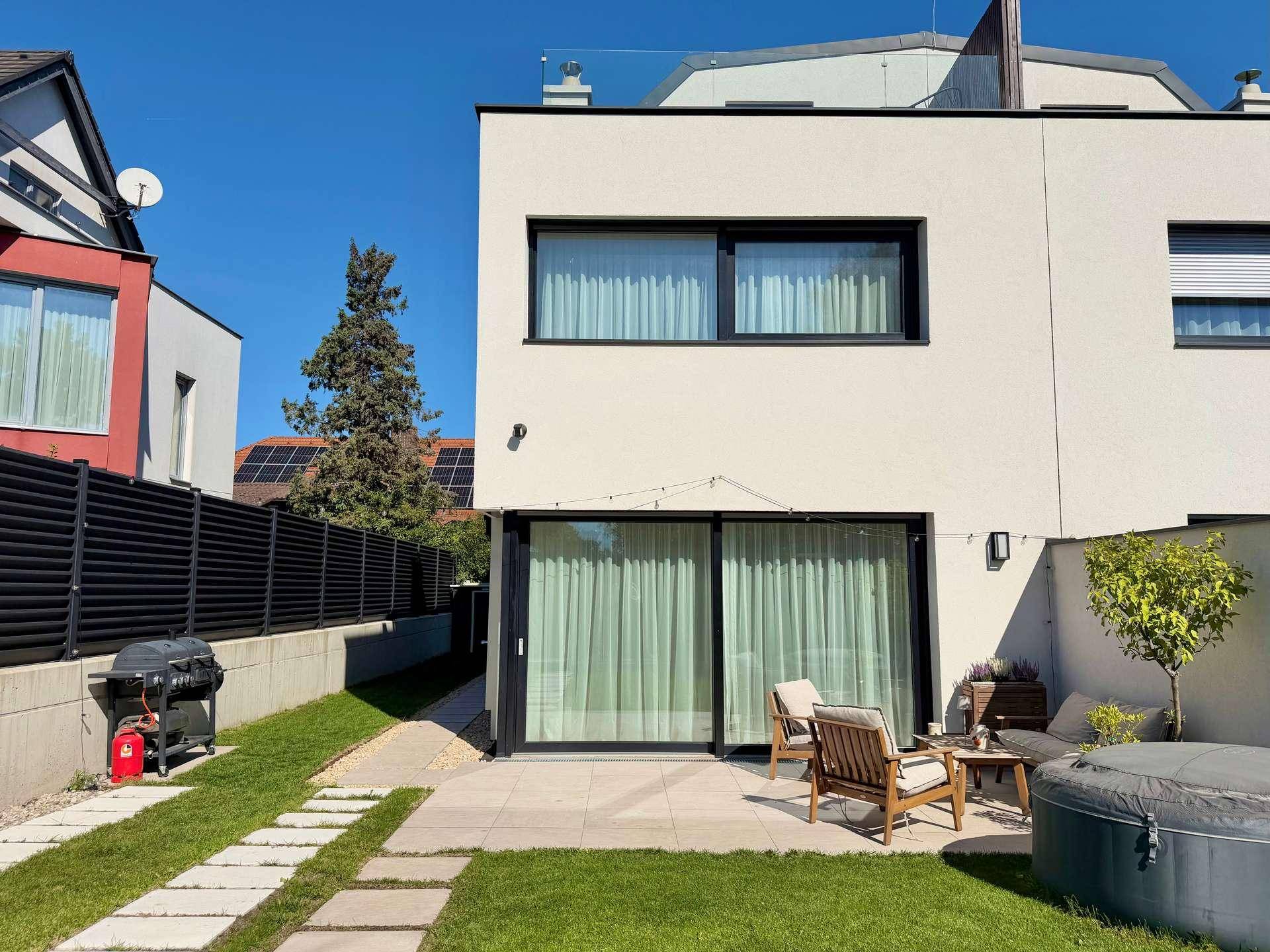 Detailansicht der Terrasse mit bequemen Gartenmöbeln und einem aufblasbaren Whirlpool im Garten.