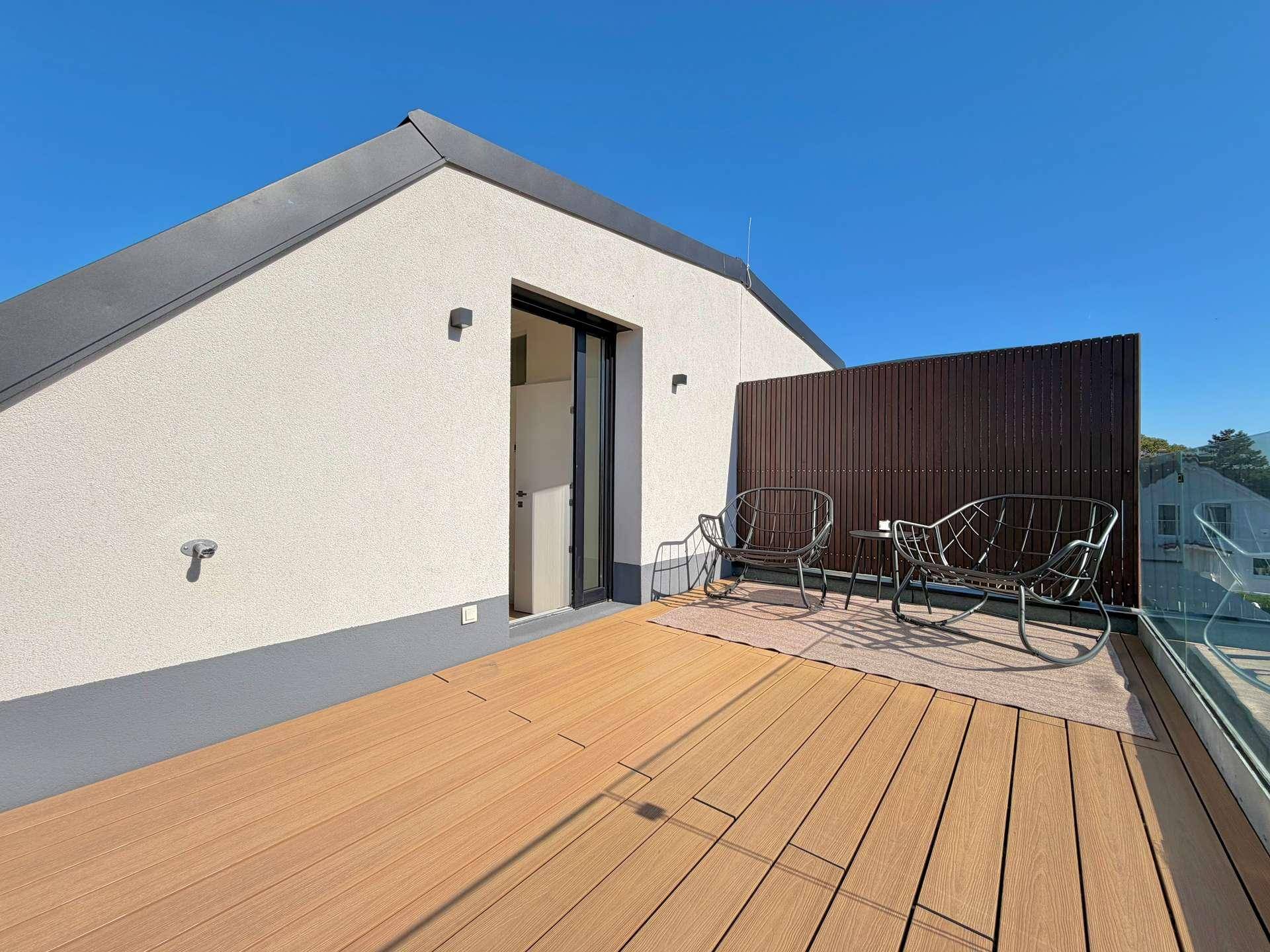 Sonnige Dachterrasse mit Holzbelag und bequemen Sitzgelegenheiten für entspannte Stunden.