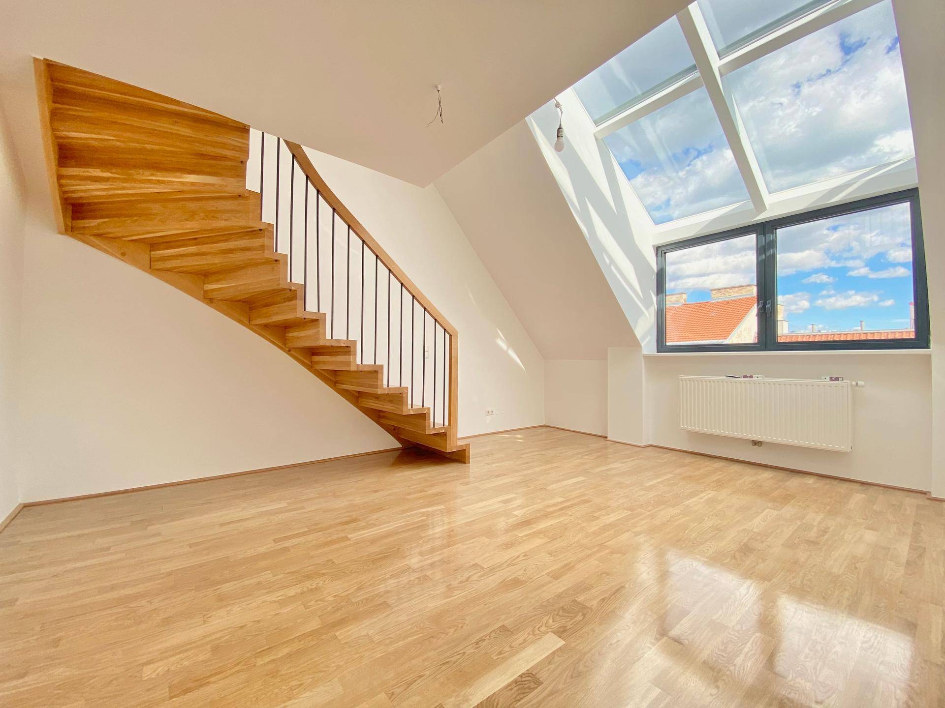 Heller Wohnbereich mit Holztreppe, Parkettboden und großen Dachfenstern für viel Tageslicht.