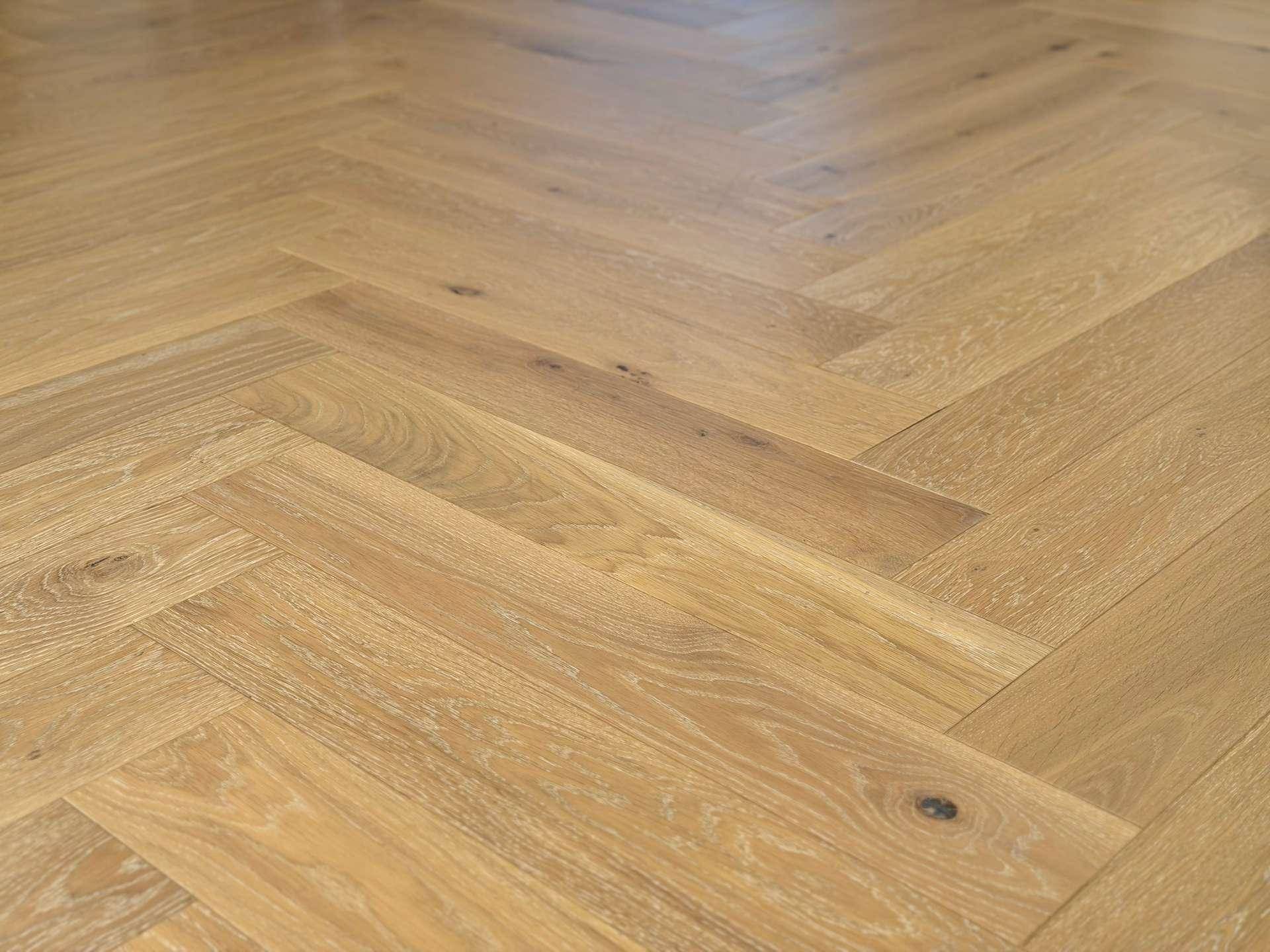 Nahaufnahme des eleganten Fischgrätparketts aus hellem Holz.