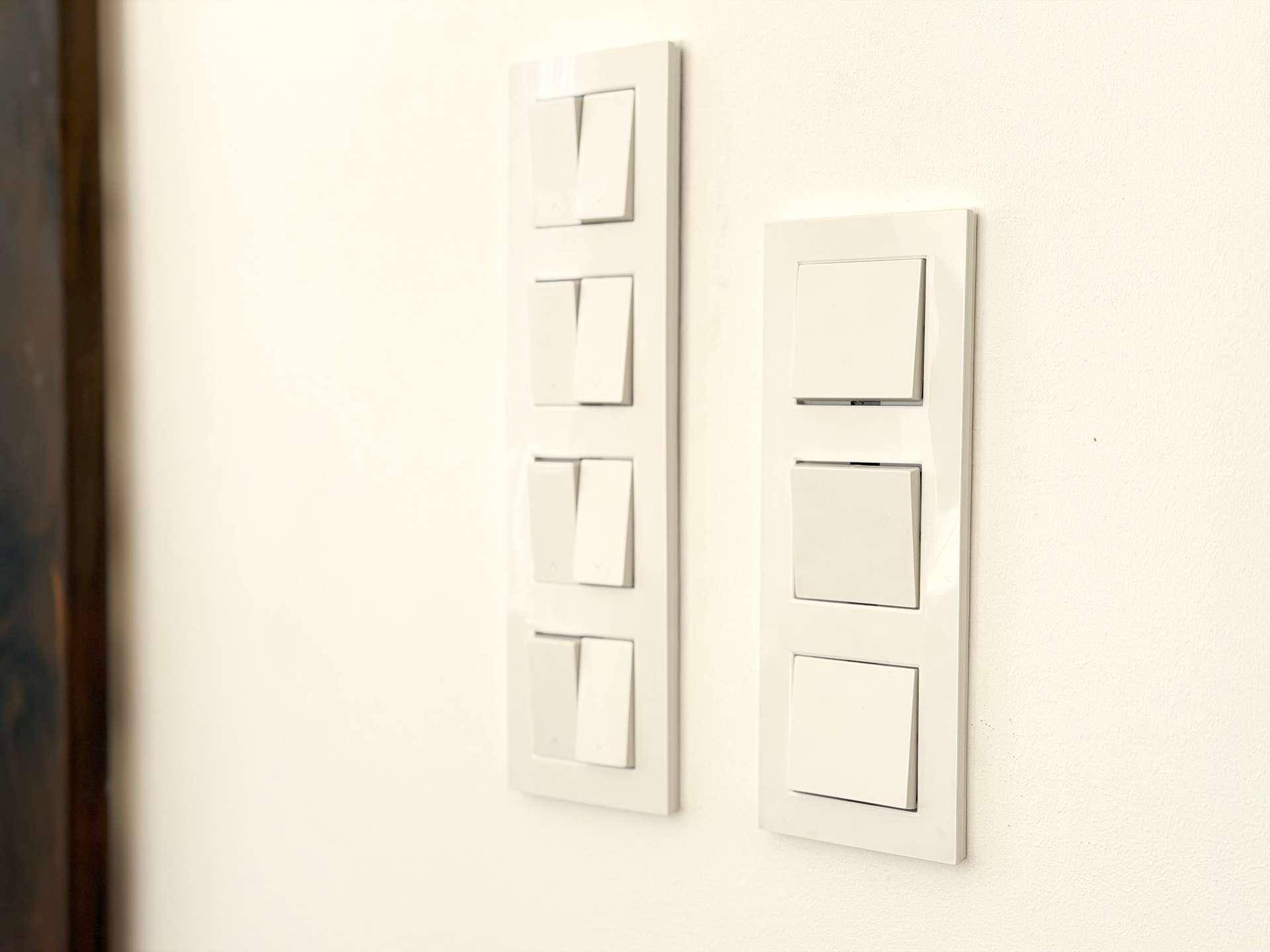 Detailaufnahme von modernen Lichtschaltern an einer weißen Wand.