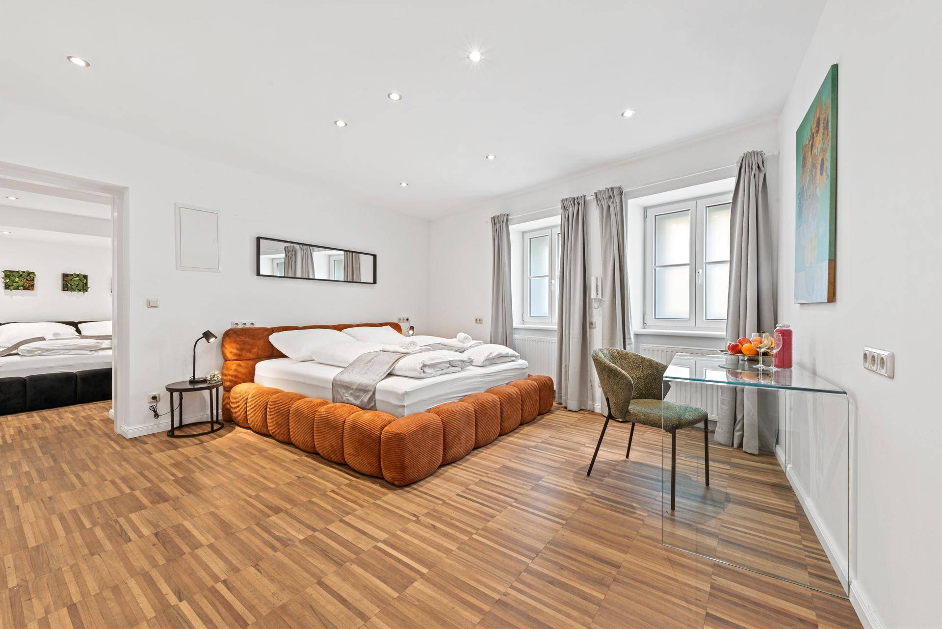 Helles Schlafzimmer mit modernem Bett, Schreibtisch und warmem Holzfußboden.