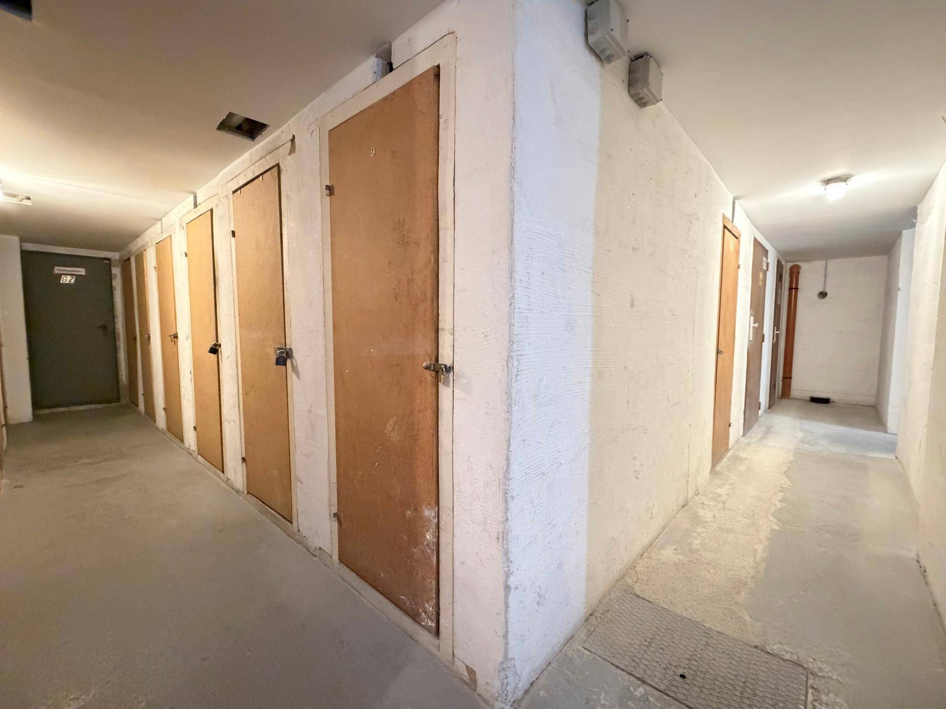 Kellerabteile mit Holztüren und Betonwänden, die zusätzlichen Stauraum bieten.