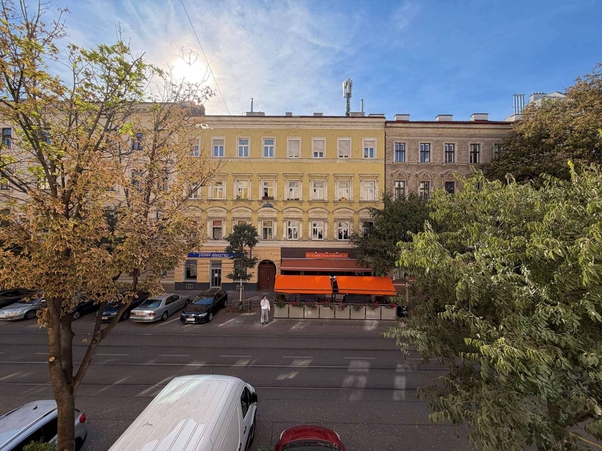 Blick von oben auf eine belebte Straße mit parkenden Autos und historischen Gebäuden.