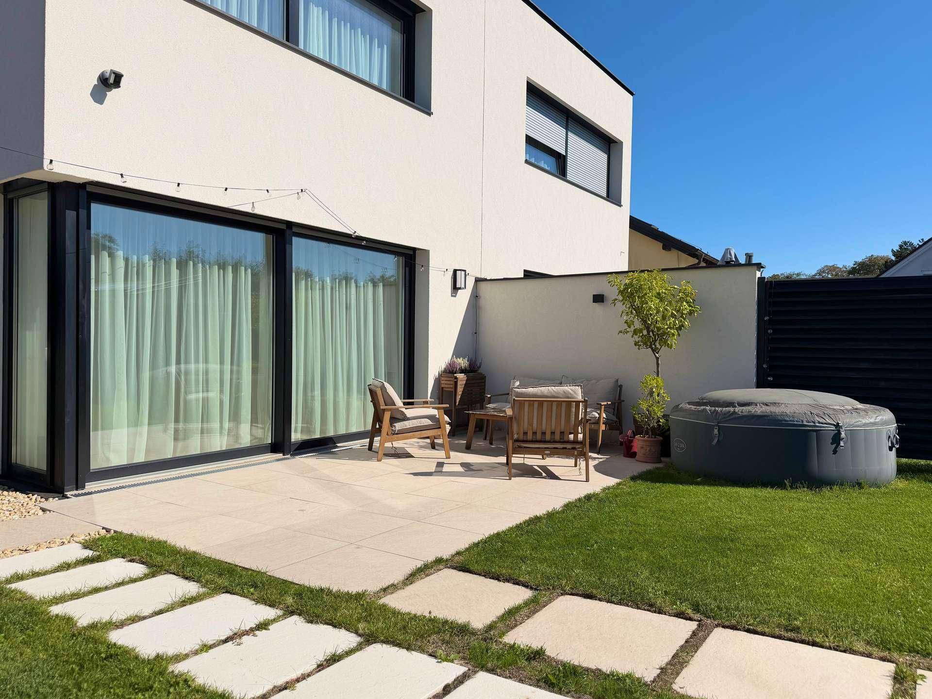 Moderne Terrasse mit Gartenmöbeln, Whirlpool und Zugang zum Wohnbereich des Hauses.