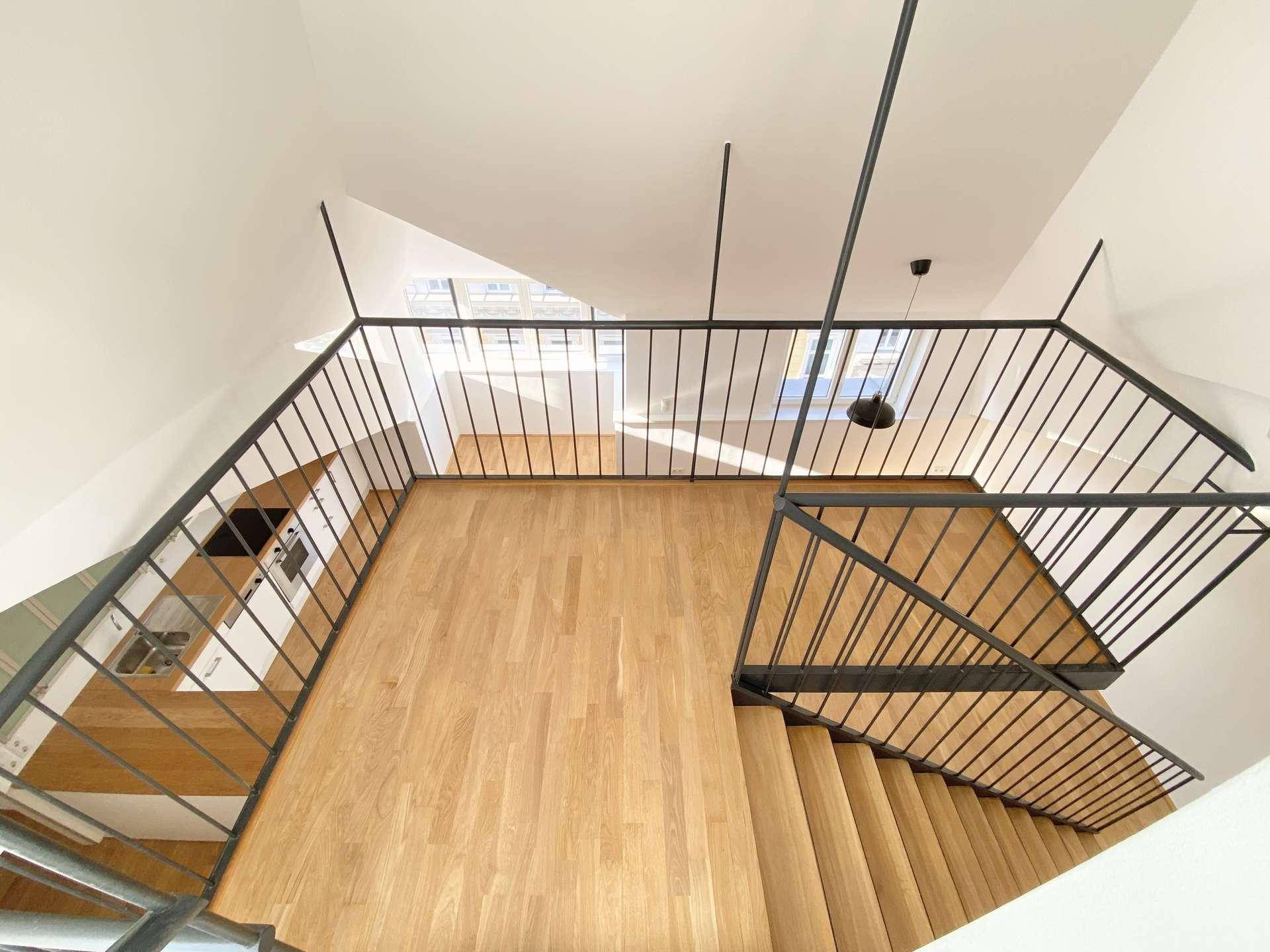 Blick von oben auf den offenen Wohnbereich mit Holzboden und moderner Treppenkonstruktion.