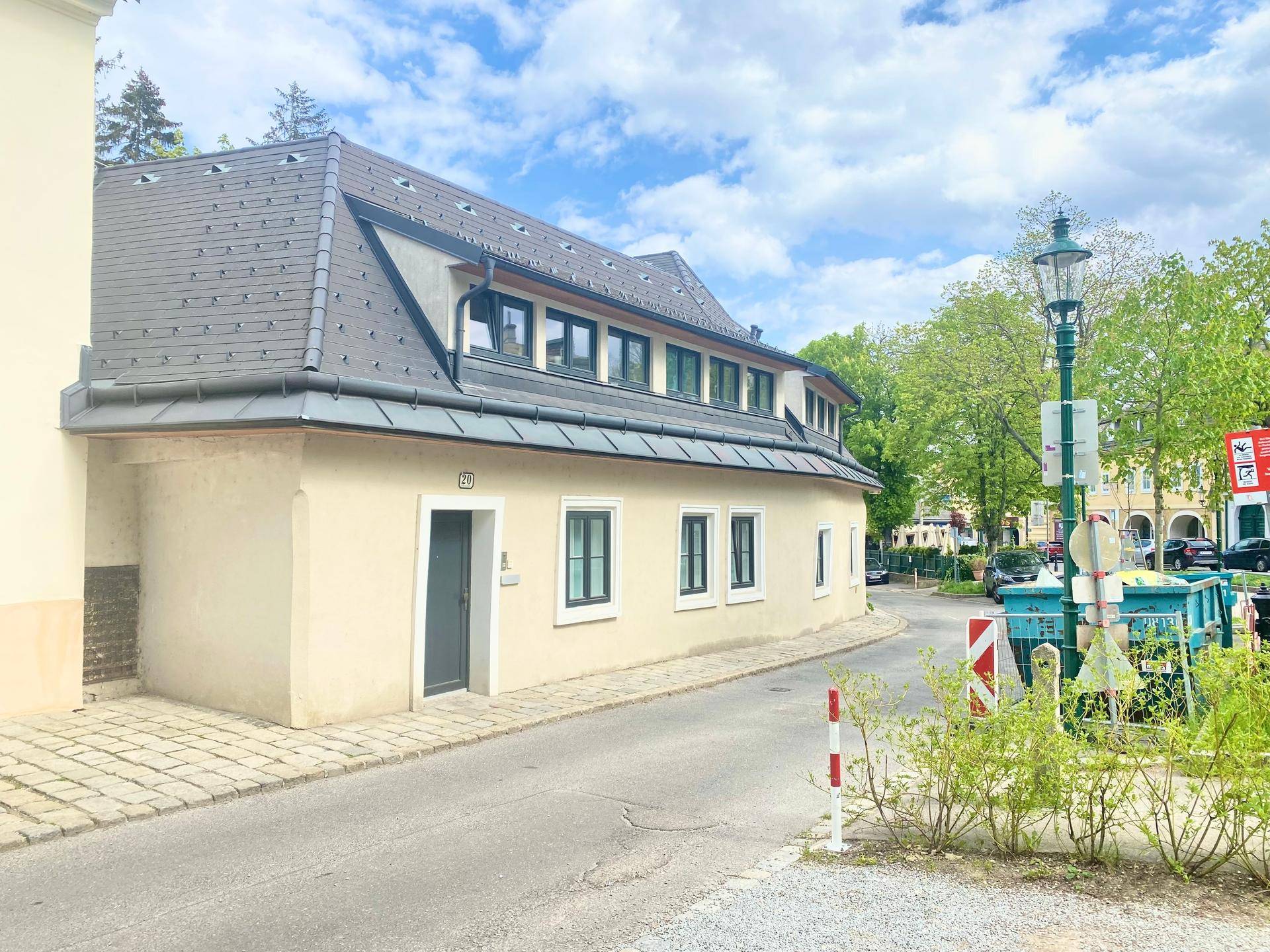Ansicht des Gebäudes von der Straße mit Mansarddach und gepflegter Fassade.
